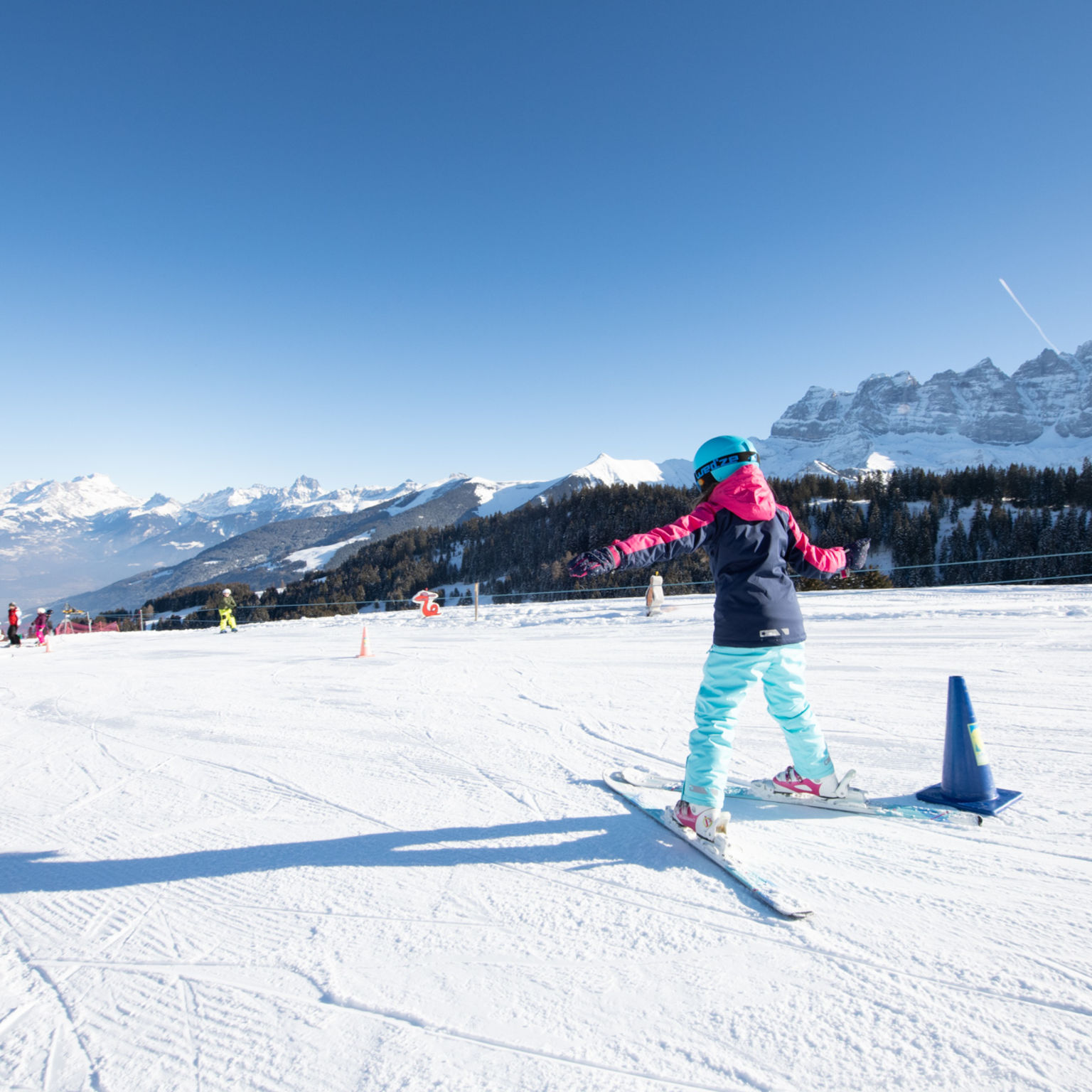 A child skiing down the snowy Sépaya slope in Morgins, with the majestic Dents du Midi in the background.