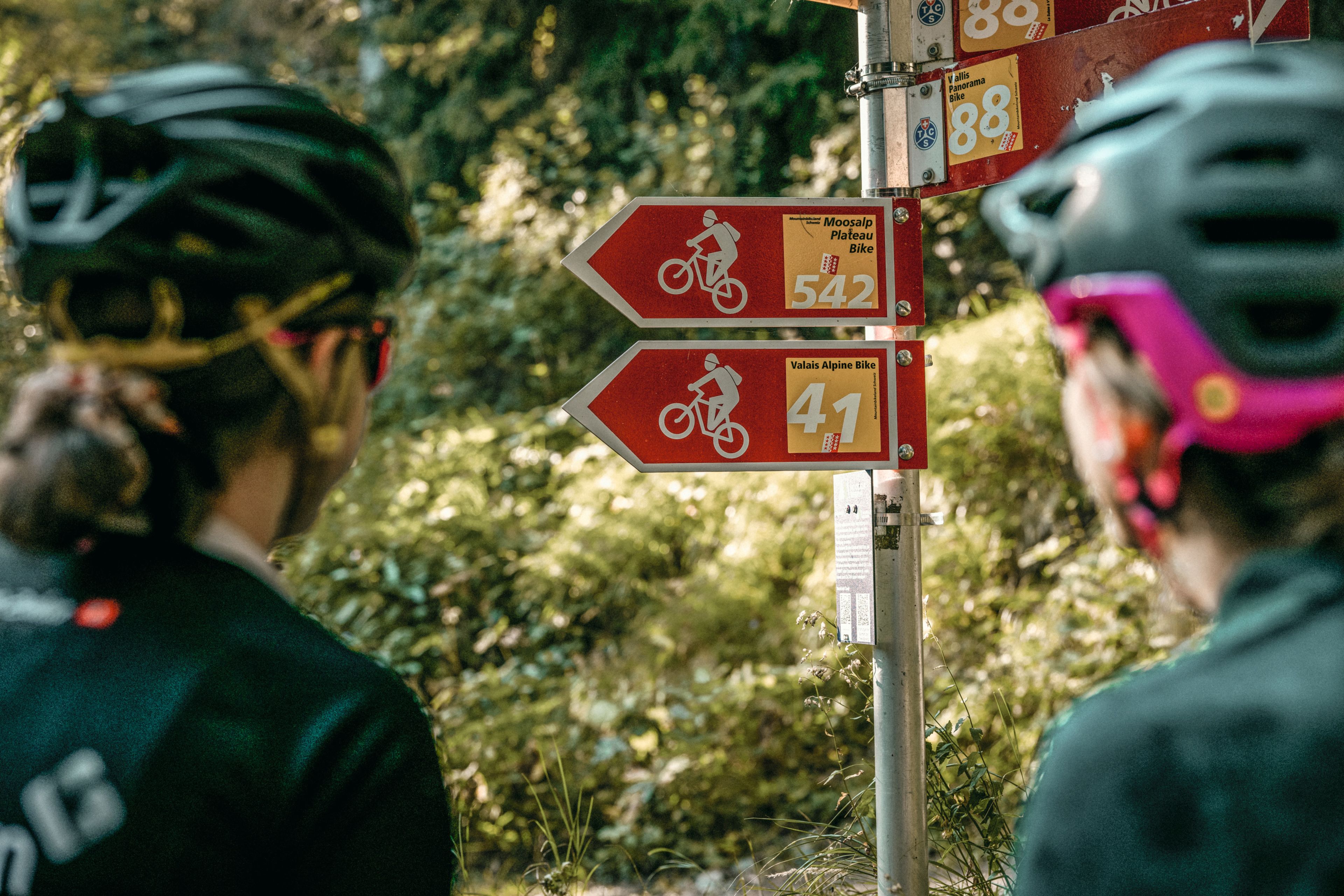 Zwei Mountainbiker, die auf Mountainbike-Schilder schauen. Wallis, Schweiz.