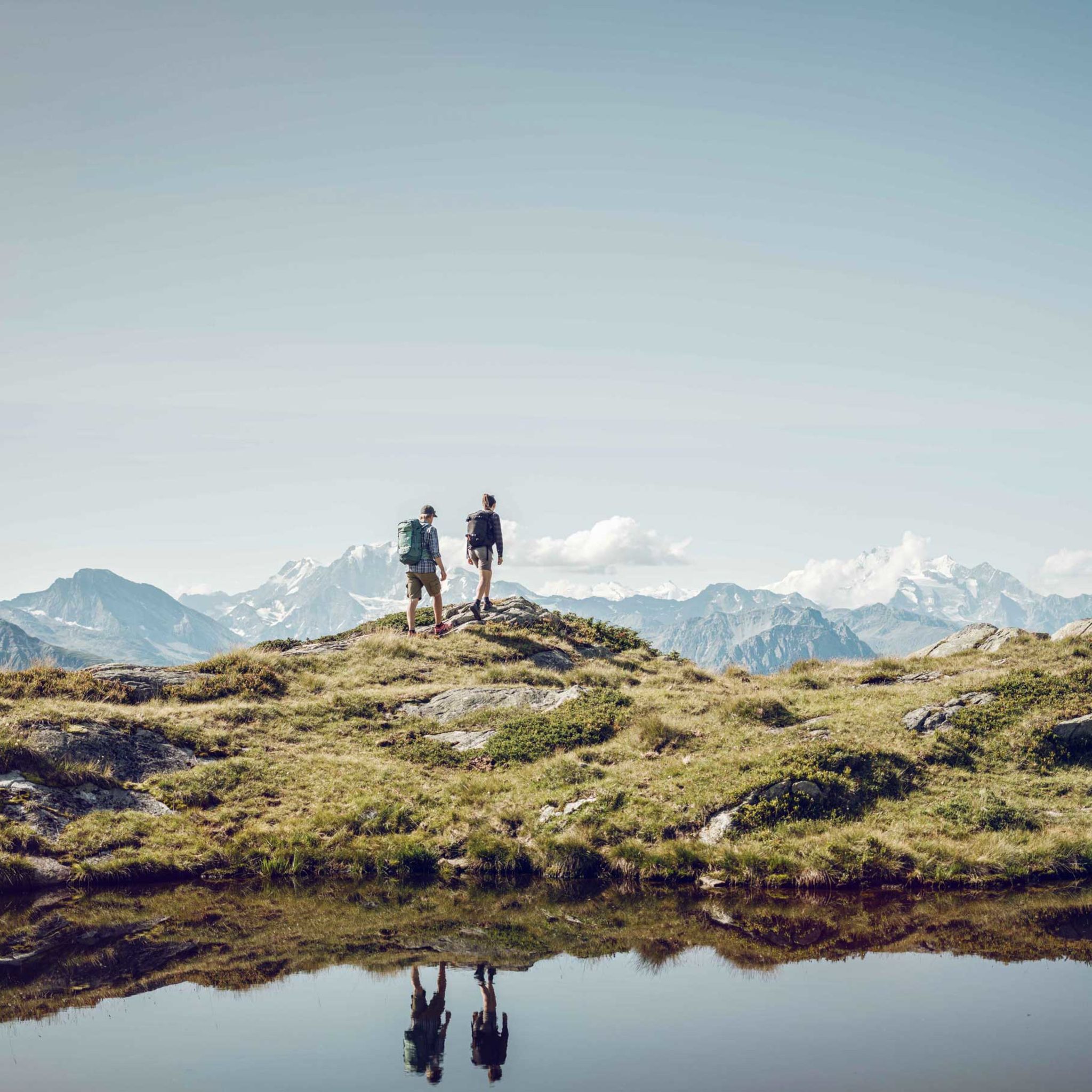 Zwei Wanderer wandern neben einem See in der Aletsch Arena. Wallis, Schweiz