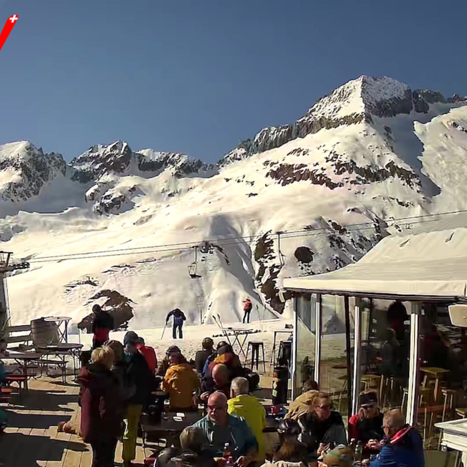 Gäste geniessen das sonnige Wetter beim Après-Ski im Ricco’s Iglu auf der Belalp mit Blick auf die verschneiten Berge