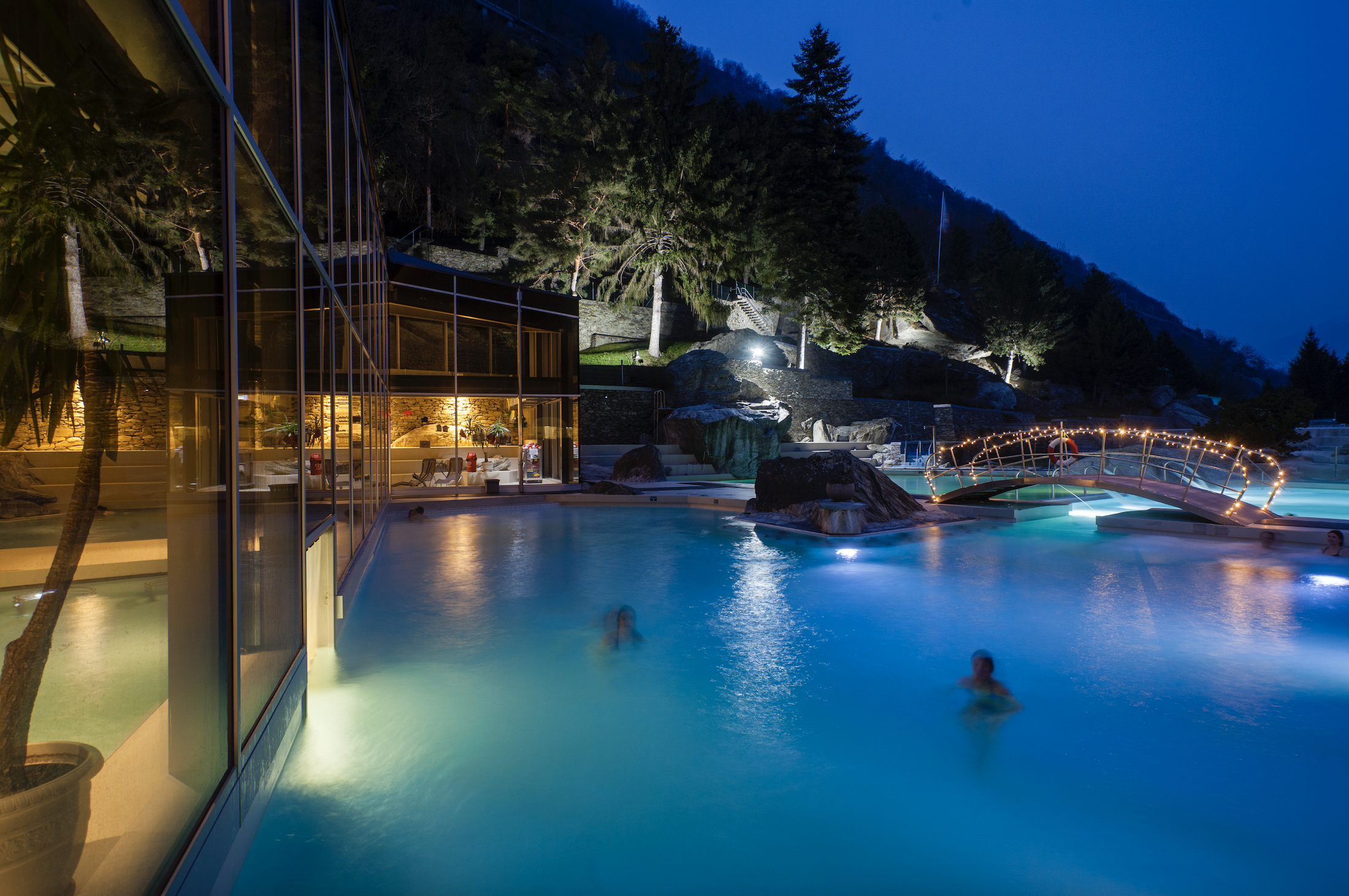 Des gens se baignent le soir avec la lune aux bains thermaux de Brigerbad. Valais, Suisse