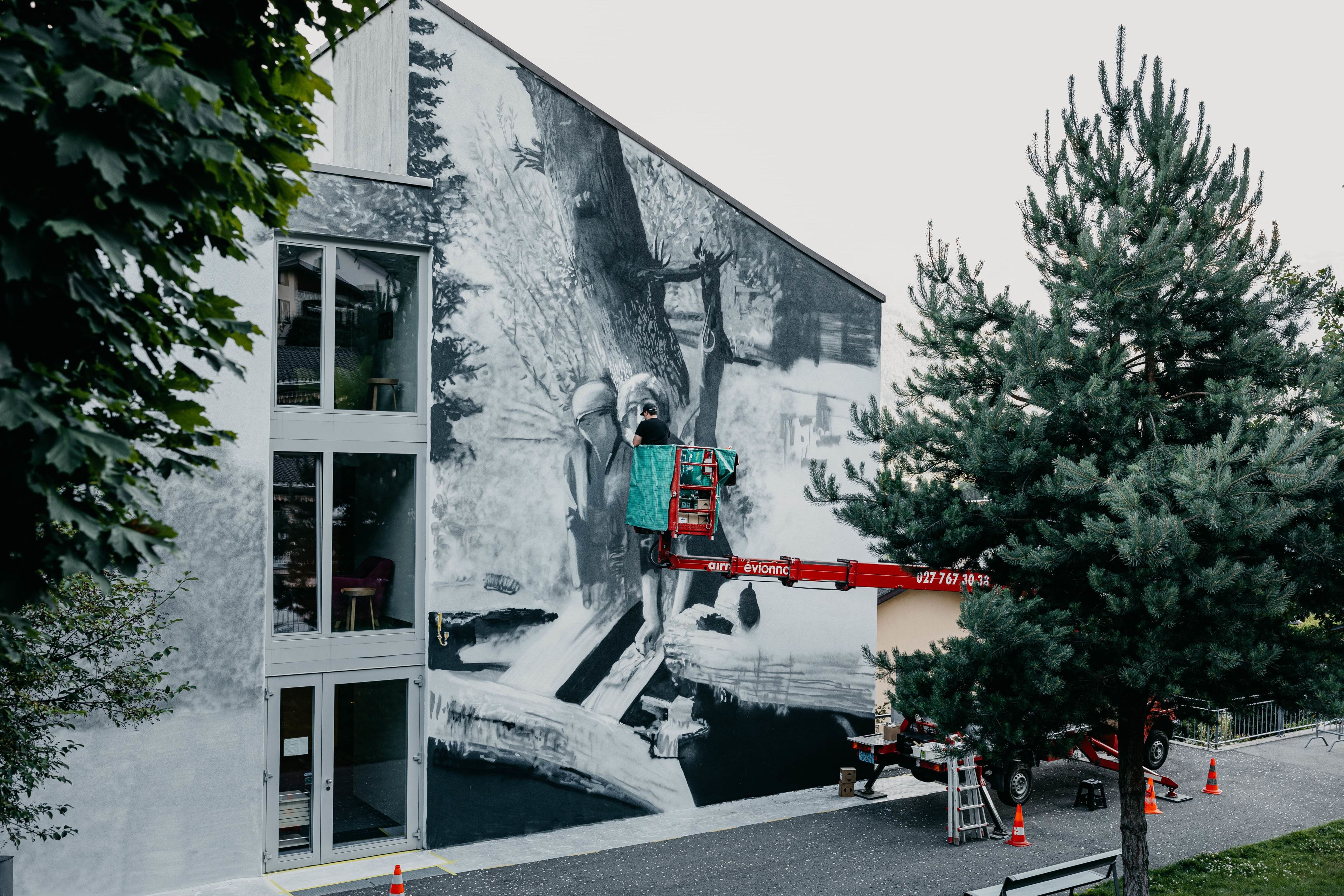 The graffiti artist Jasm One at work on his wall painting on the façade of the Foyer Sœur Louise Bron in Fully, Valais, Switzerland