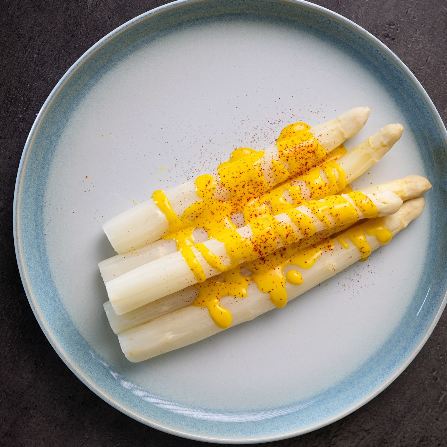 Asperges blanches servies avec une sauce au safran dans une assiette