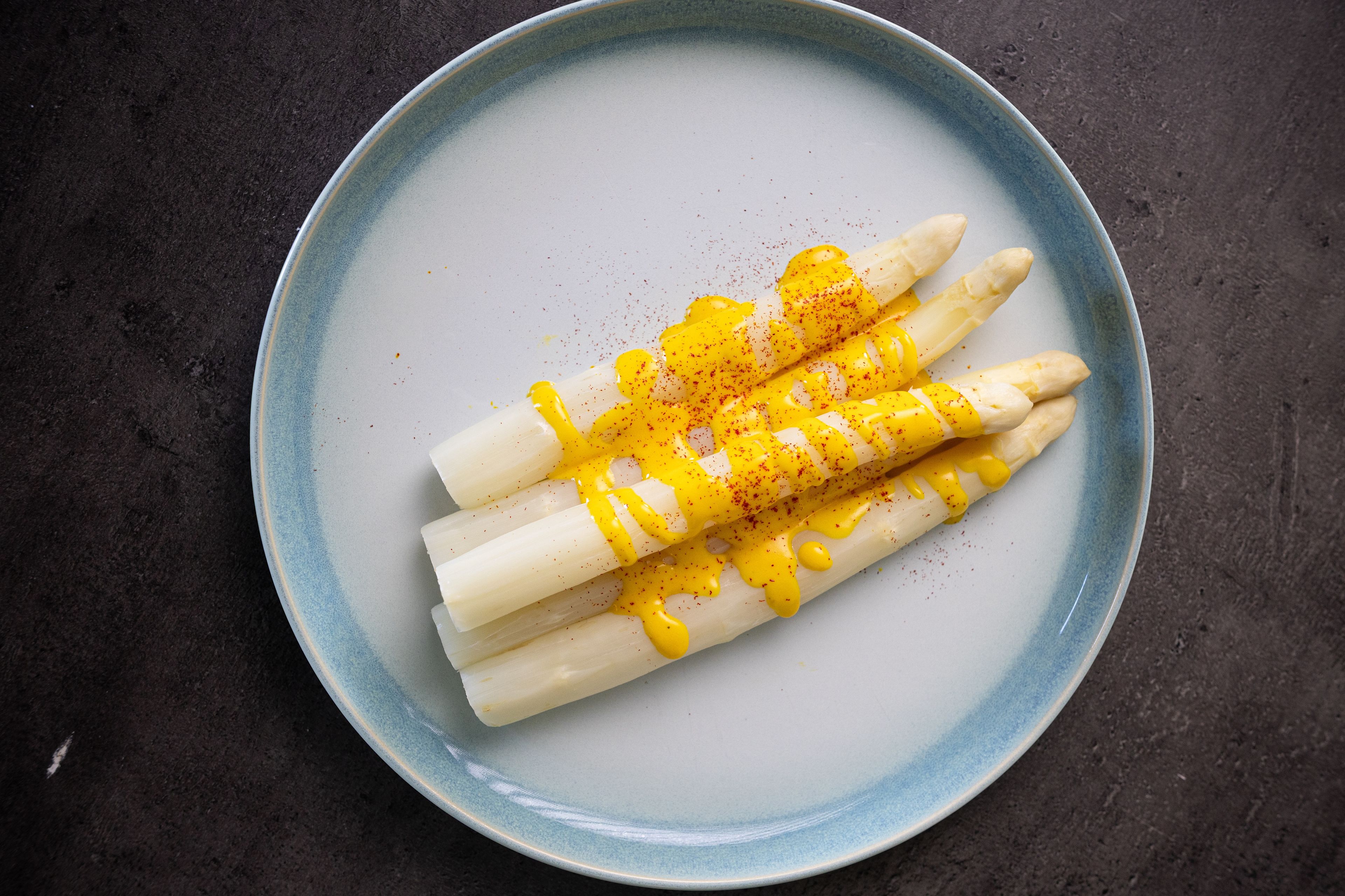 Asperges blanches servies avec une sauce au safran dans une assiette
