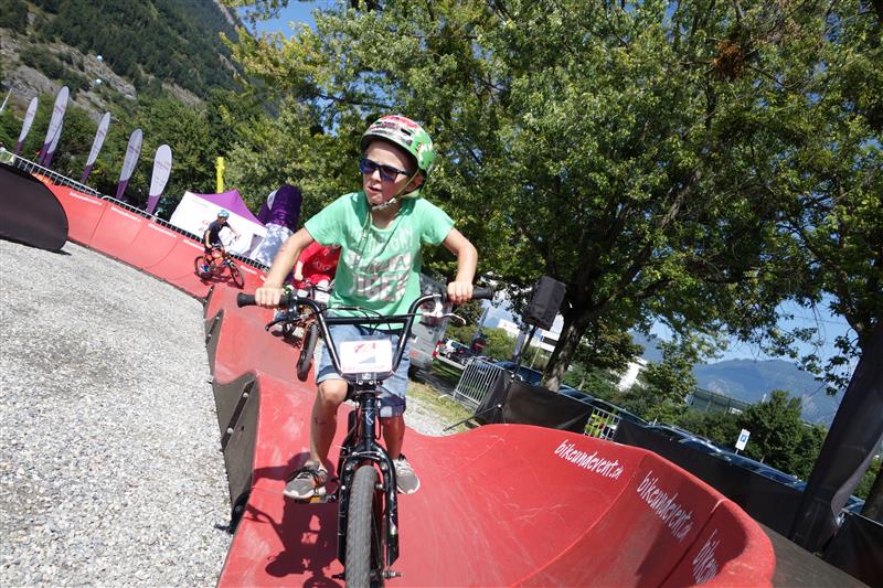 Kind fährt mit einem Fahrrad auf dem Pumptrack von Reckingen im Goms