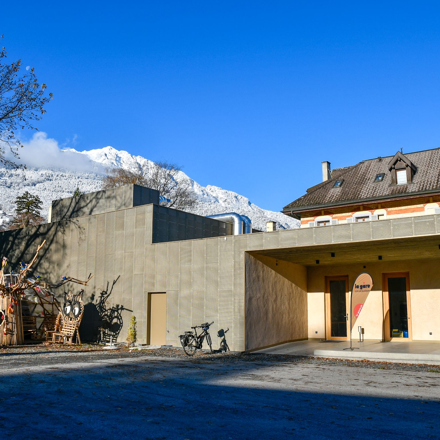Exterior view of La Gare cultural center in Monthey with modern architecture and wooden installation, Valais, Switzerland