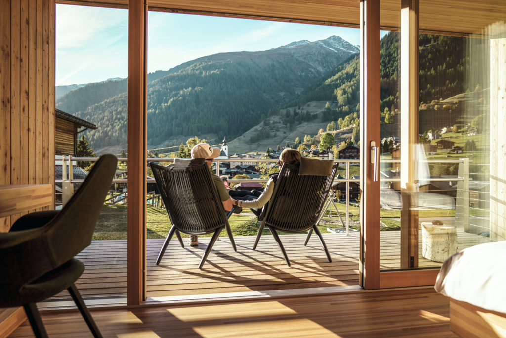 Paar entspannt sich auf der Terrasse des Hotel Glocke in Reckingen mit Blick auf die Walliser Berglandschaft
