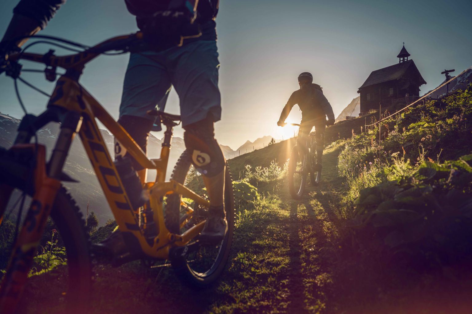 Zwei Mountainbiker beenden ihren Mountainbike-Tag mit der untergehenden Sonne im Lötschental. Wallis, Schweiz
