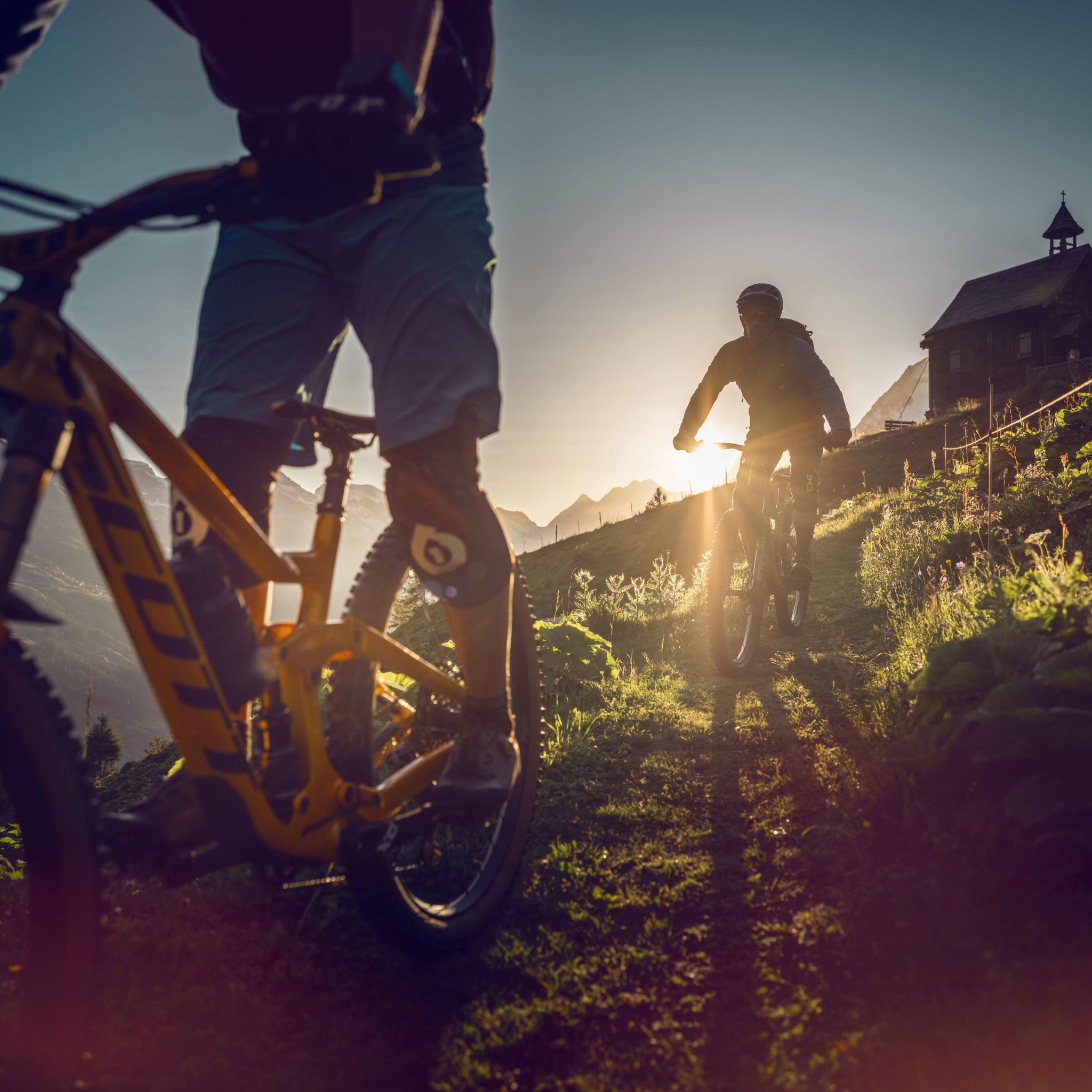 Zwei Mountainbiker beenden ihren Mountainbike-Tag mit der untergehenden Sonne im Lötschental. Wallis, Schweiz
