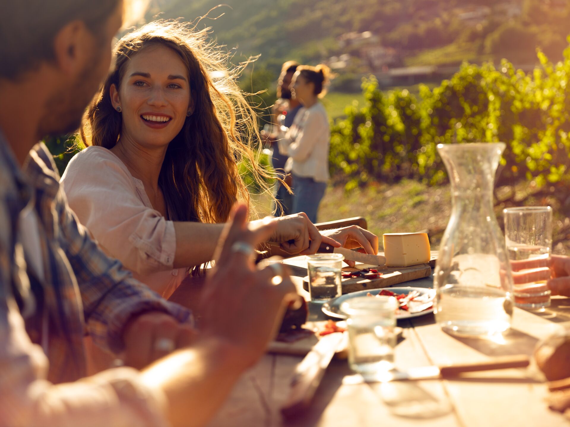 Freunde genießen gemeinsam eine Walliser Platte in den Weinbergen in der Sonne