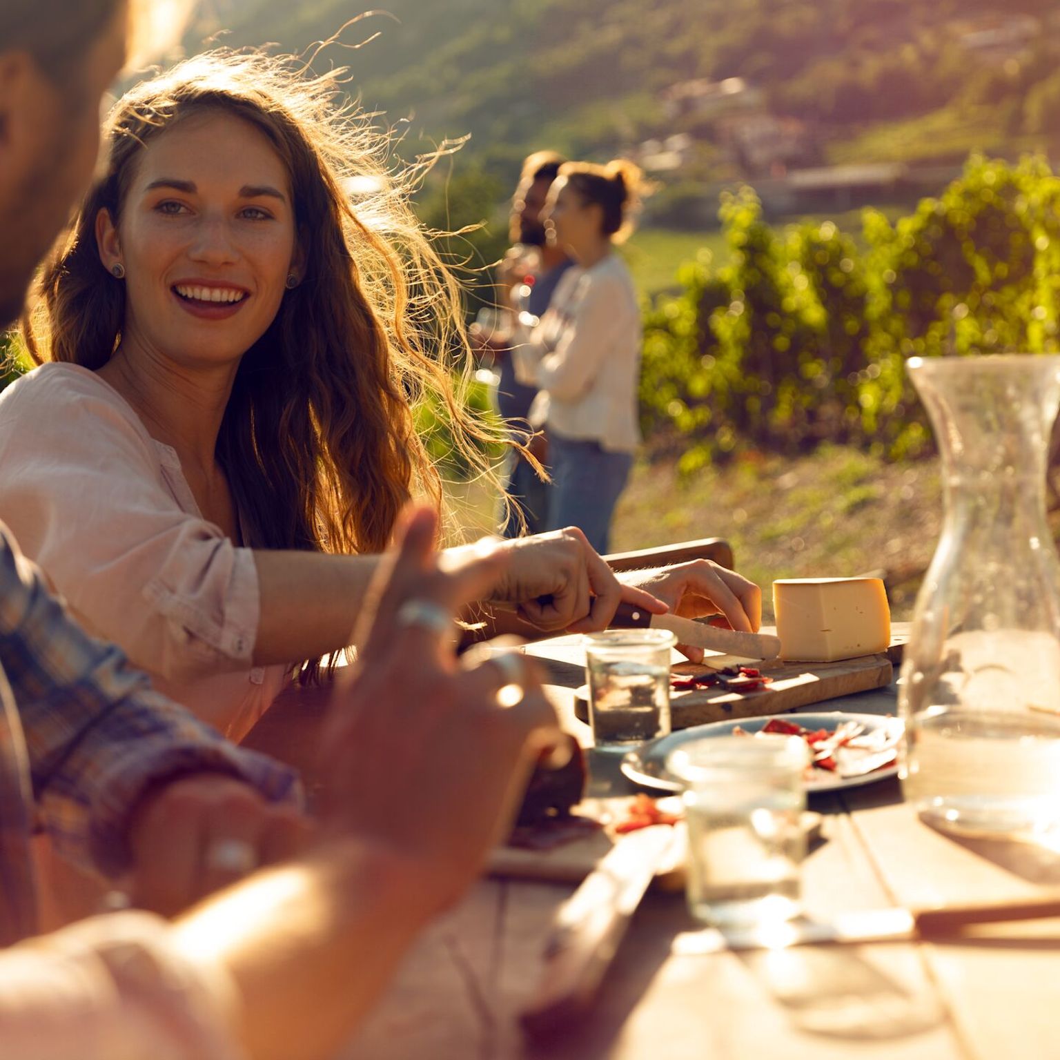 Freunde genießen gemeinsam eine Walliser Platte in den Weinbergen in der Sonne