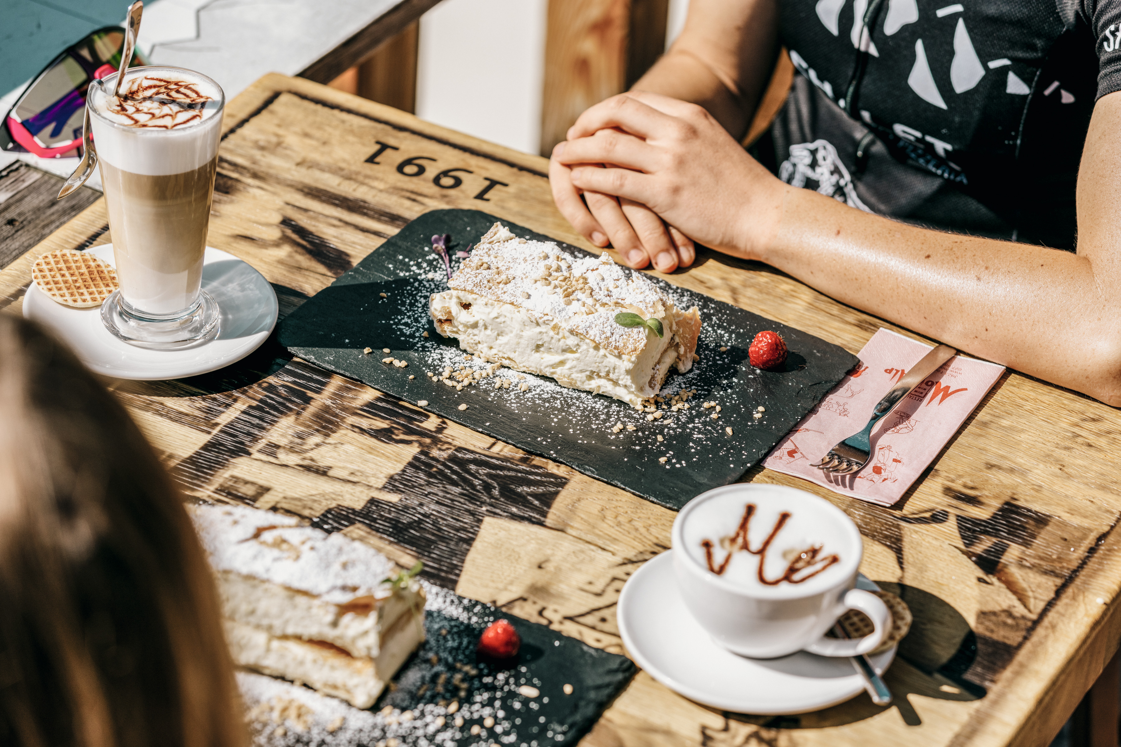 Two people enjoying a cream tart on the terrace of the Moosalp restaurant. Valais, Switzerland.