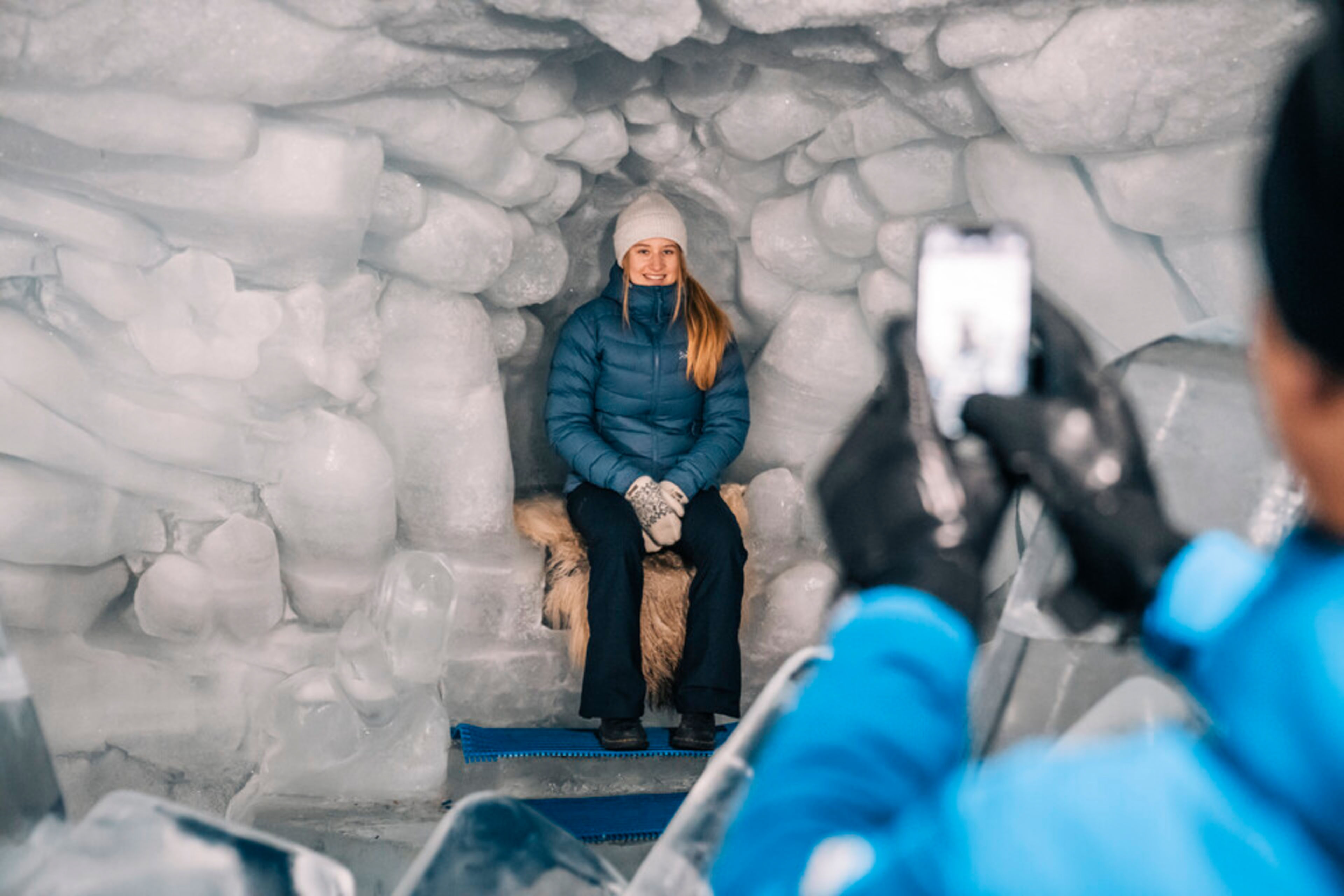 Une femme posant sur un siège en glace recouvert de peau dans une alcôve du Palais de glace de Zermatt