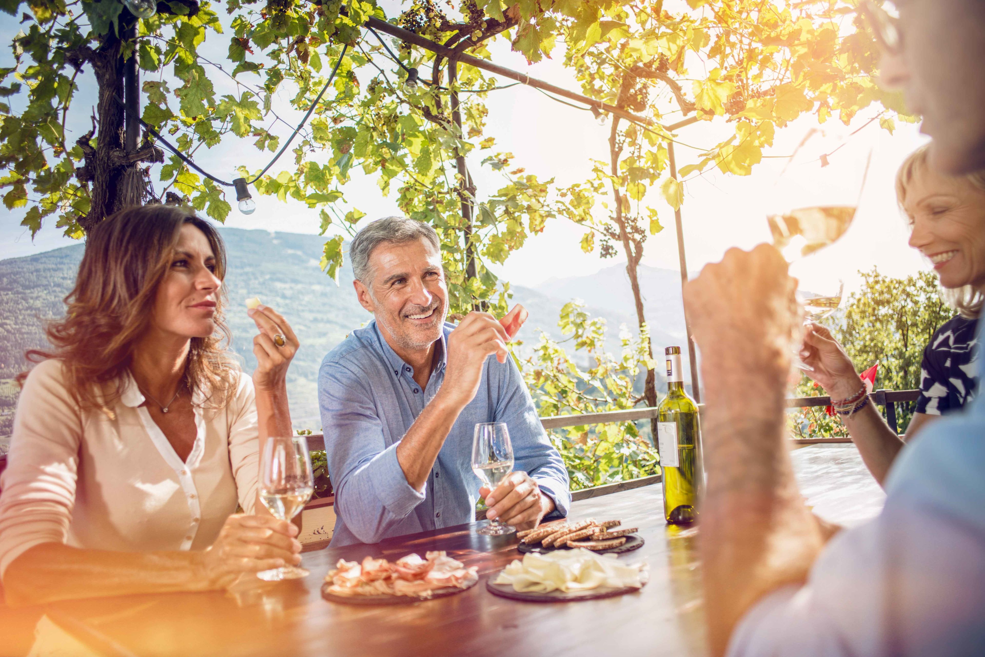 Freunde bei einem Drink und gutem Walliser Essen und Wein in einer Hütte in den Weinbergen. Wallis. Schweiz