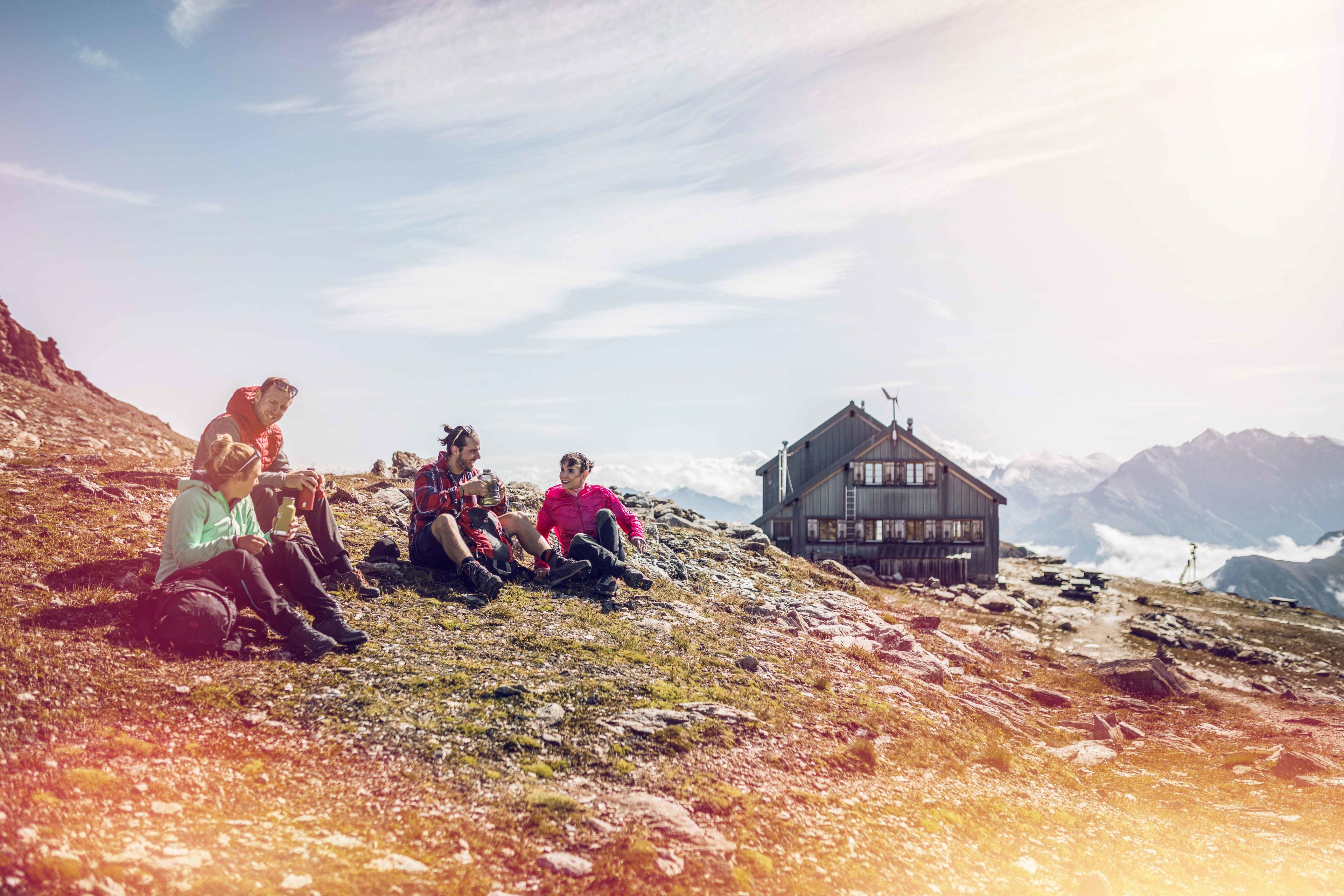 Des randonneurs font une pause boisson devant la cabane Becs de Bosson après une randonnée. Valais, Suisse