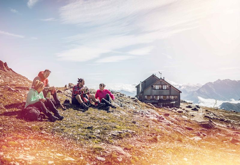 Hikers have a drink break in front of the Becs de Bosson hut after a hike. Valais, Switzerland