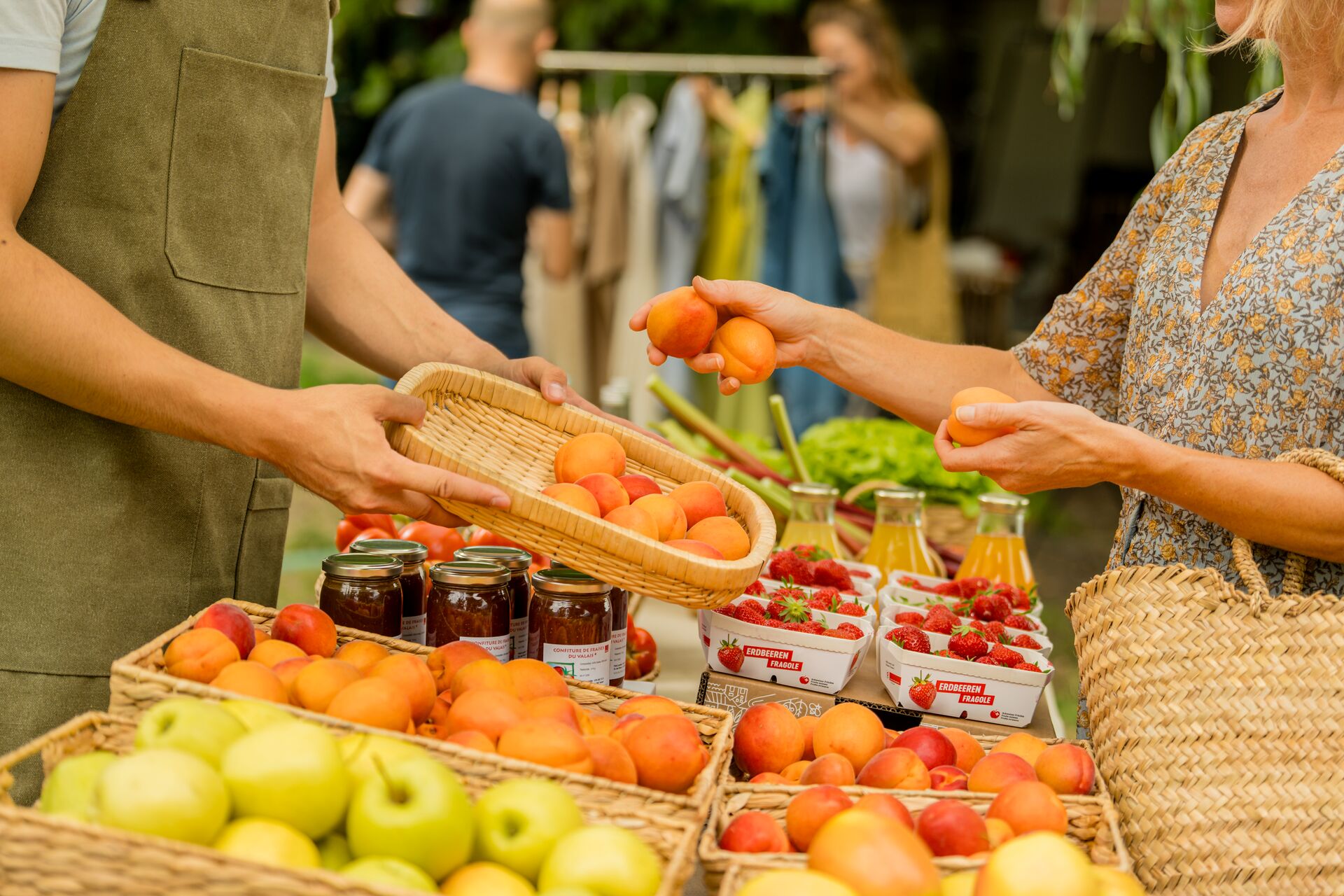 Personen kaufen frische Walliser Früchte und regionale Produkte an einem Marktstand