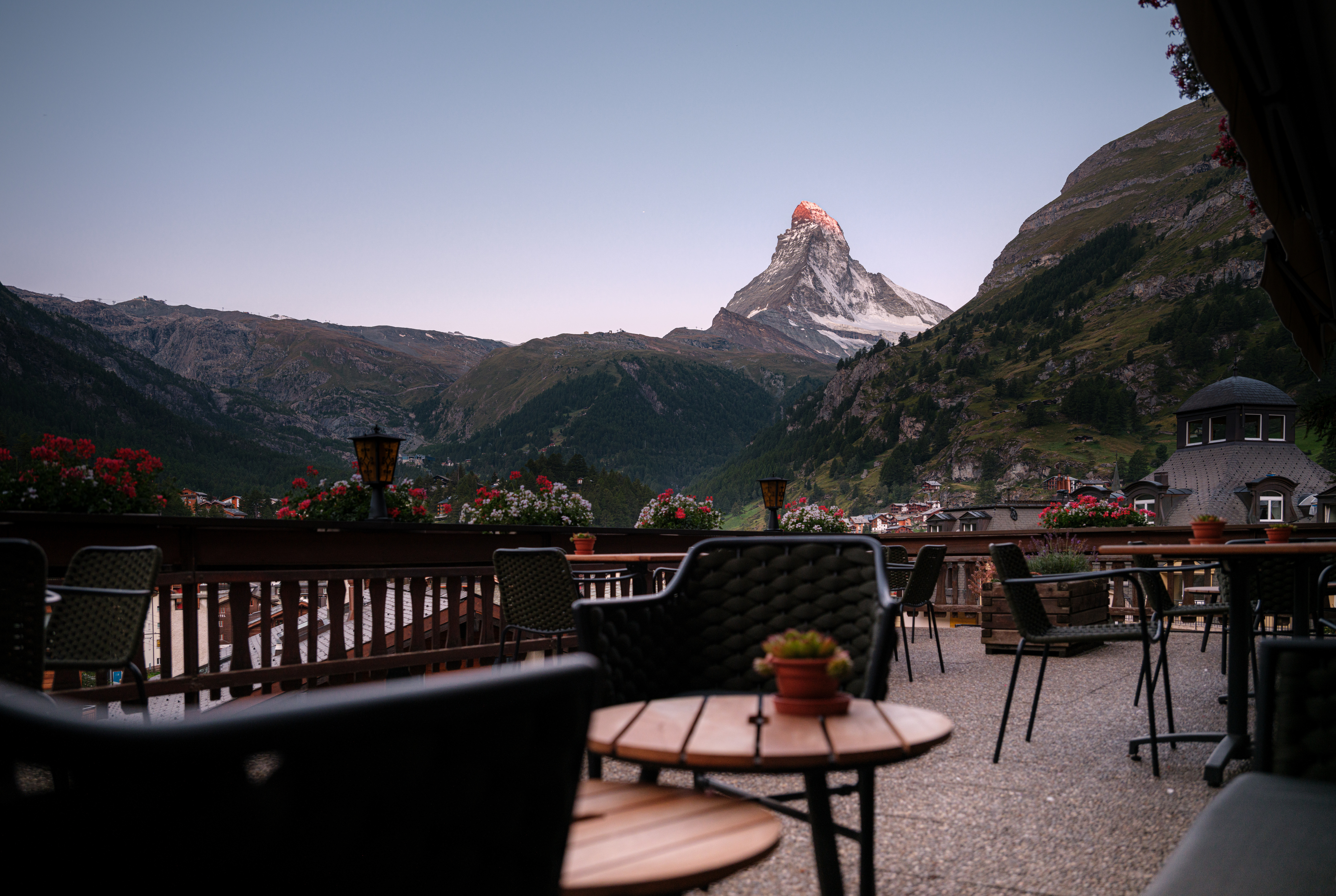 Terrasse des Hotel Bella Vista in Zermatt mit Tischen, Blumen und Blick auf das Matterhorn im Abendlicht