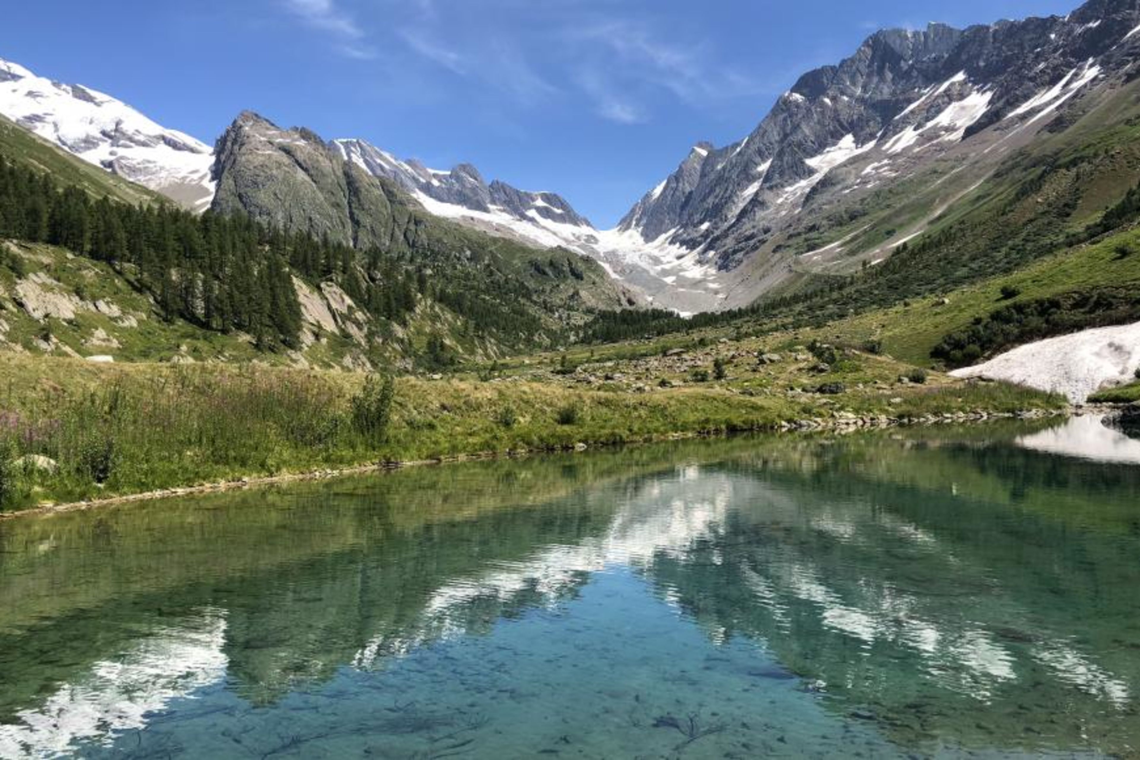 Hikers at the border of Grundsee, mountain lake in Lötschental, Valais