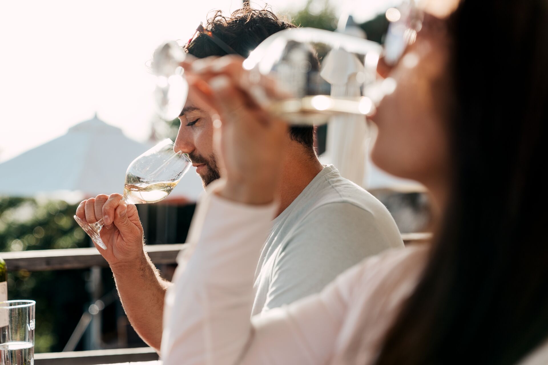 Eine Frau und ein Mann degustieren Wesswein auf einer Terrasse in Sitten im Wallis