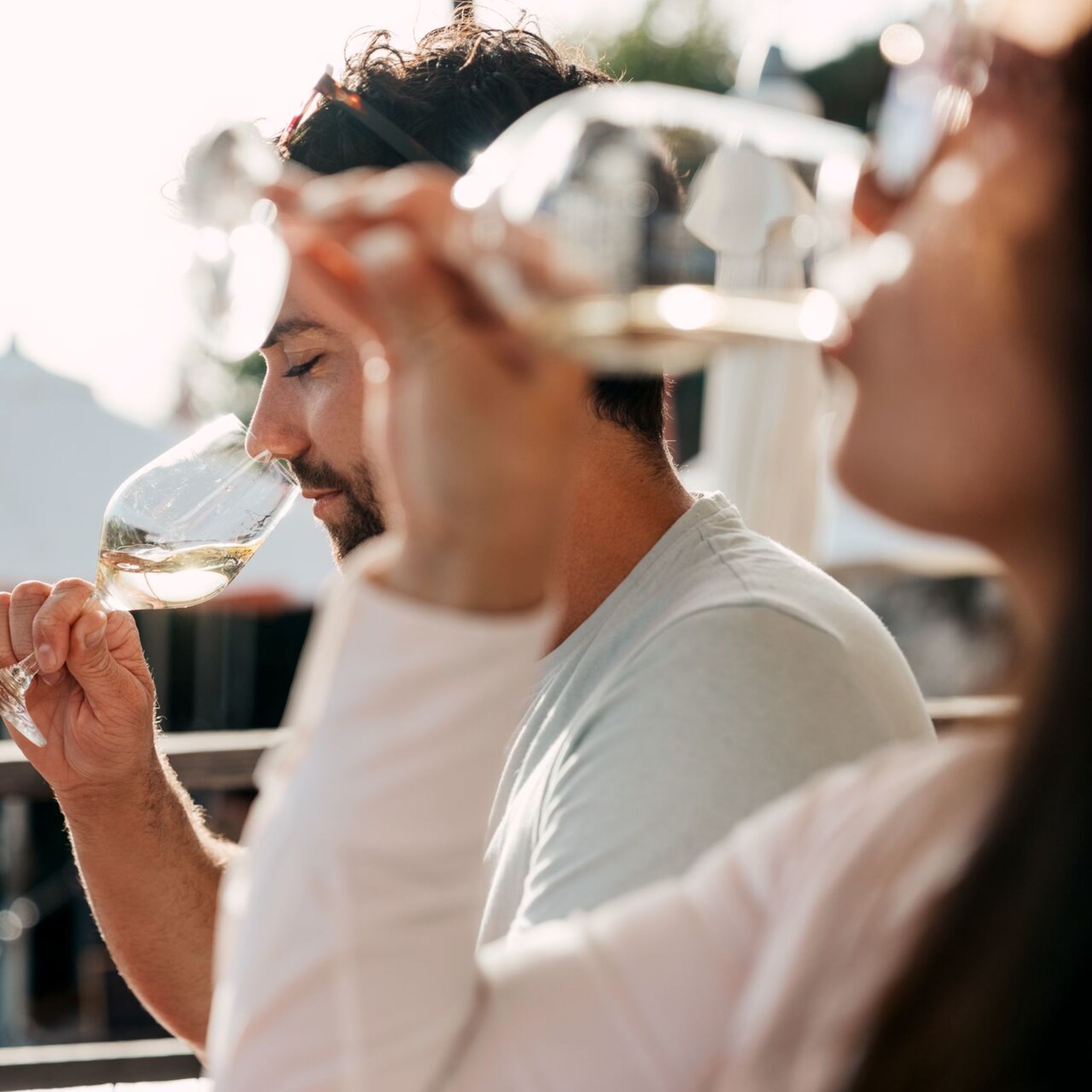Eine Frau und ein Mann degustieren Wesswein auf einer Terrasse in Sitten im Wallis