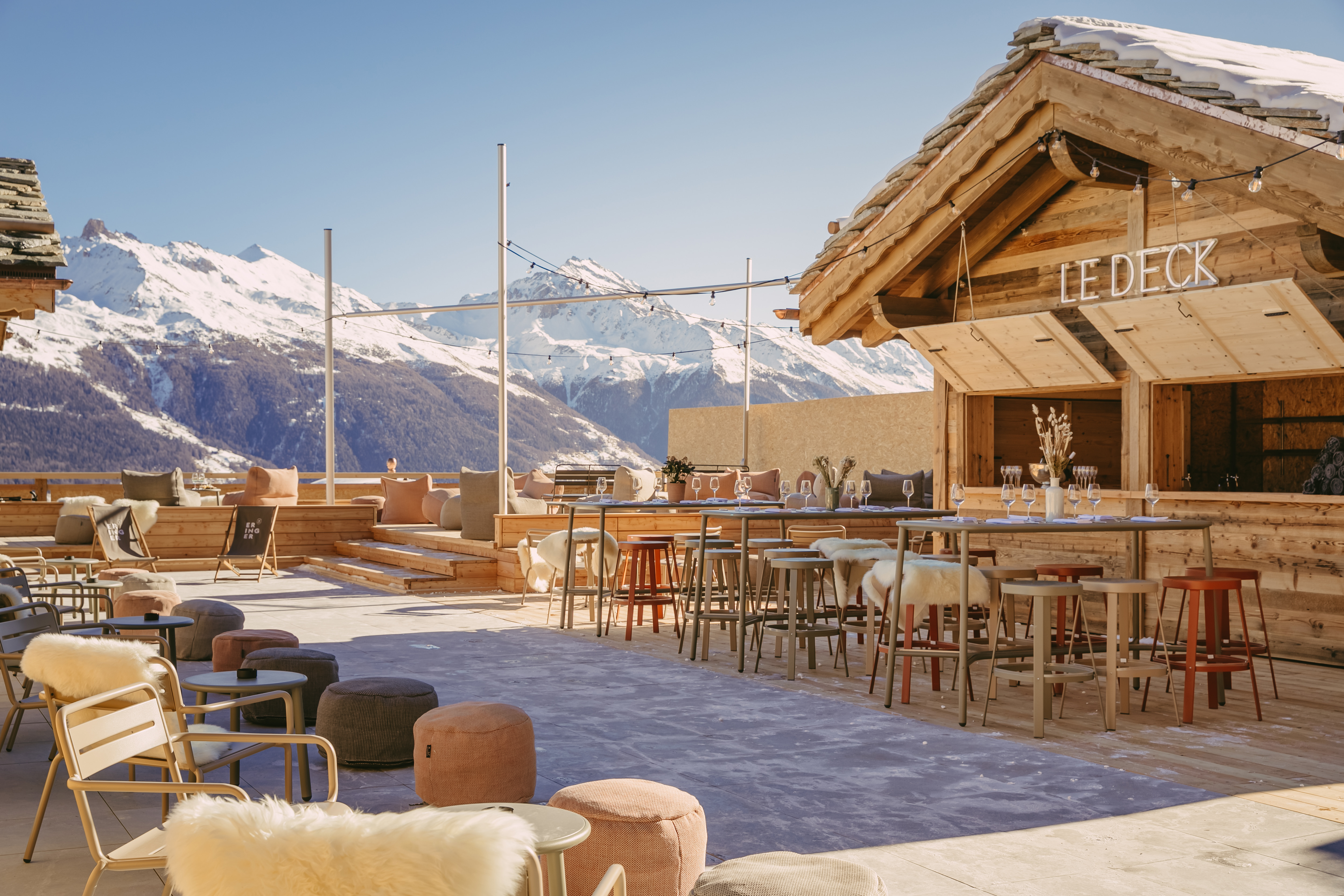 Sonnenterrasse Le Deck mit stilvoller Einrichtung und Blick auf verschneite Berge im Hotel Eringer in Hérémence