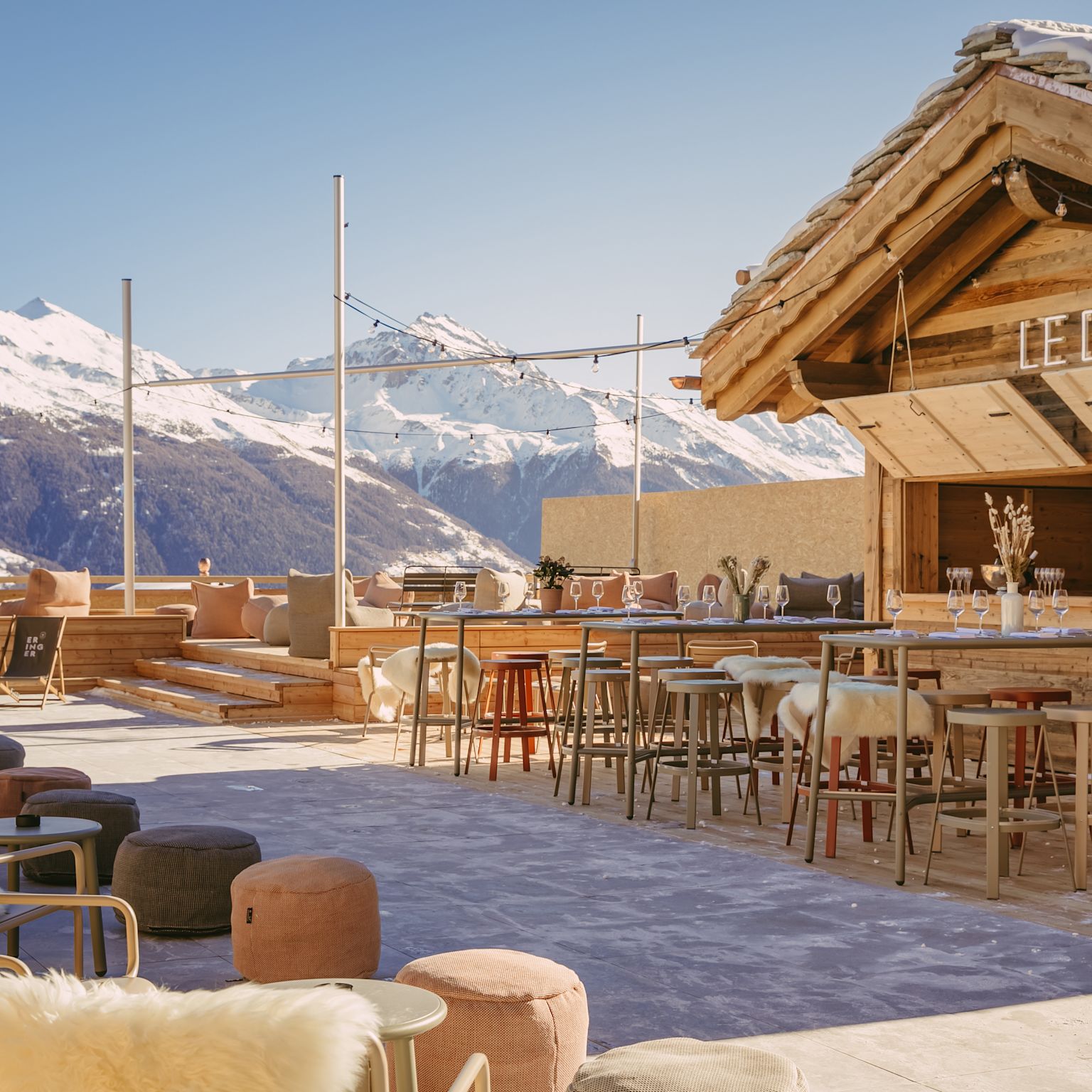 Sonnenterrasse Le Deck mit stilvoller Einrichtung und Blick auf verschneite Berge im Hotel Eringer in Hérémence
