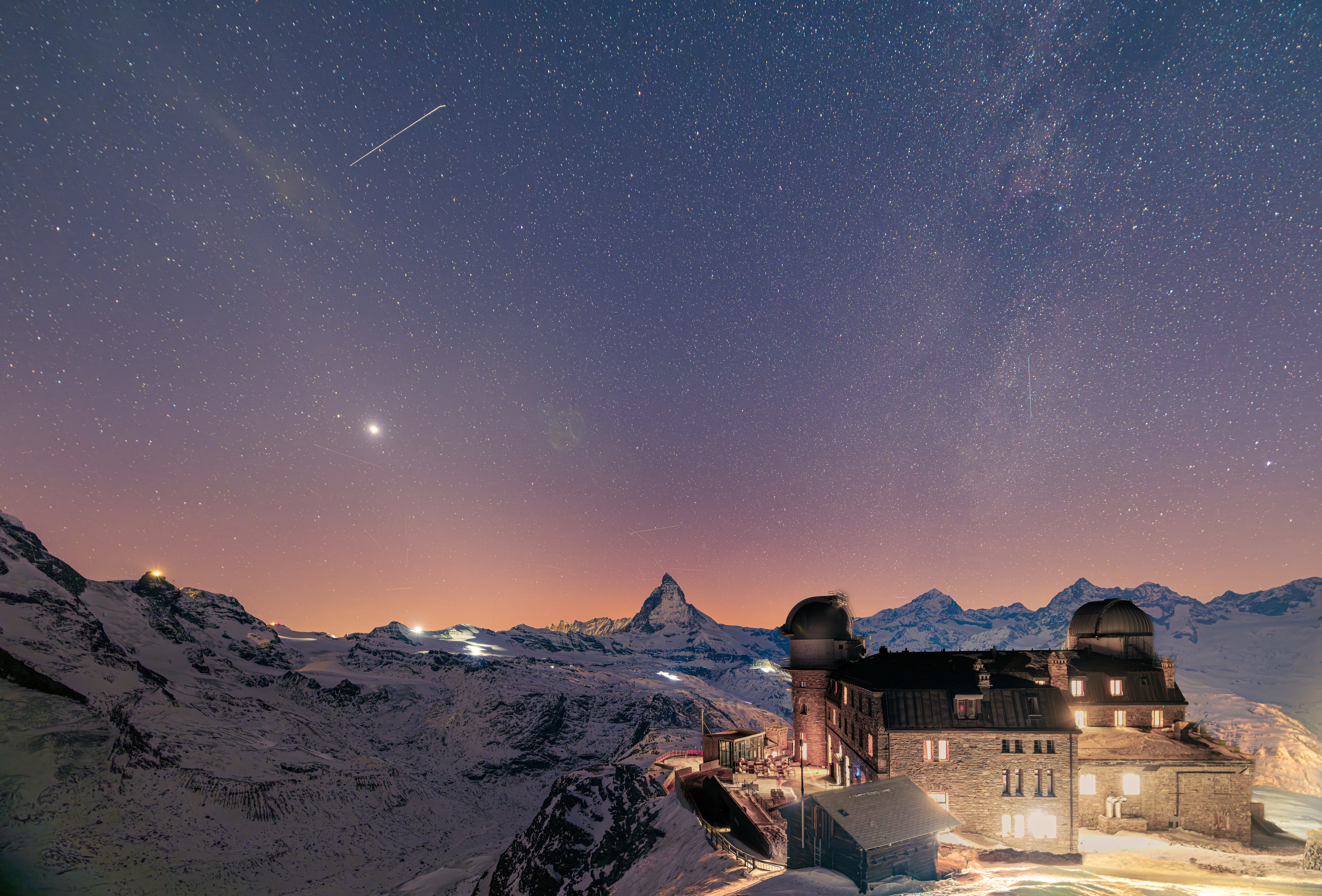 Vue nocturne depuis le Gornergrat avec le Kulmhotel illuminé et un ciel étoilé au-dessus du Cervinn