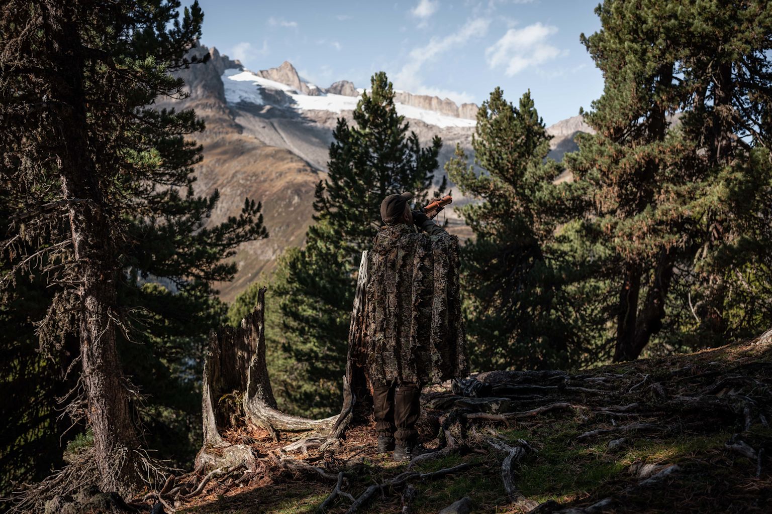 Marcel Grichting with deer caller and camouflage coat in forest, Valais, Switzerland