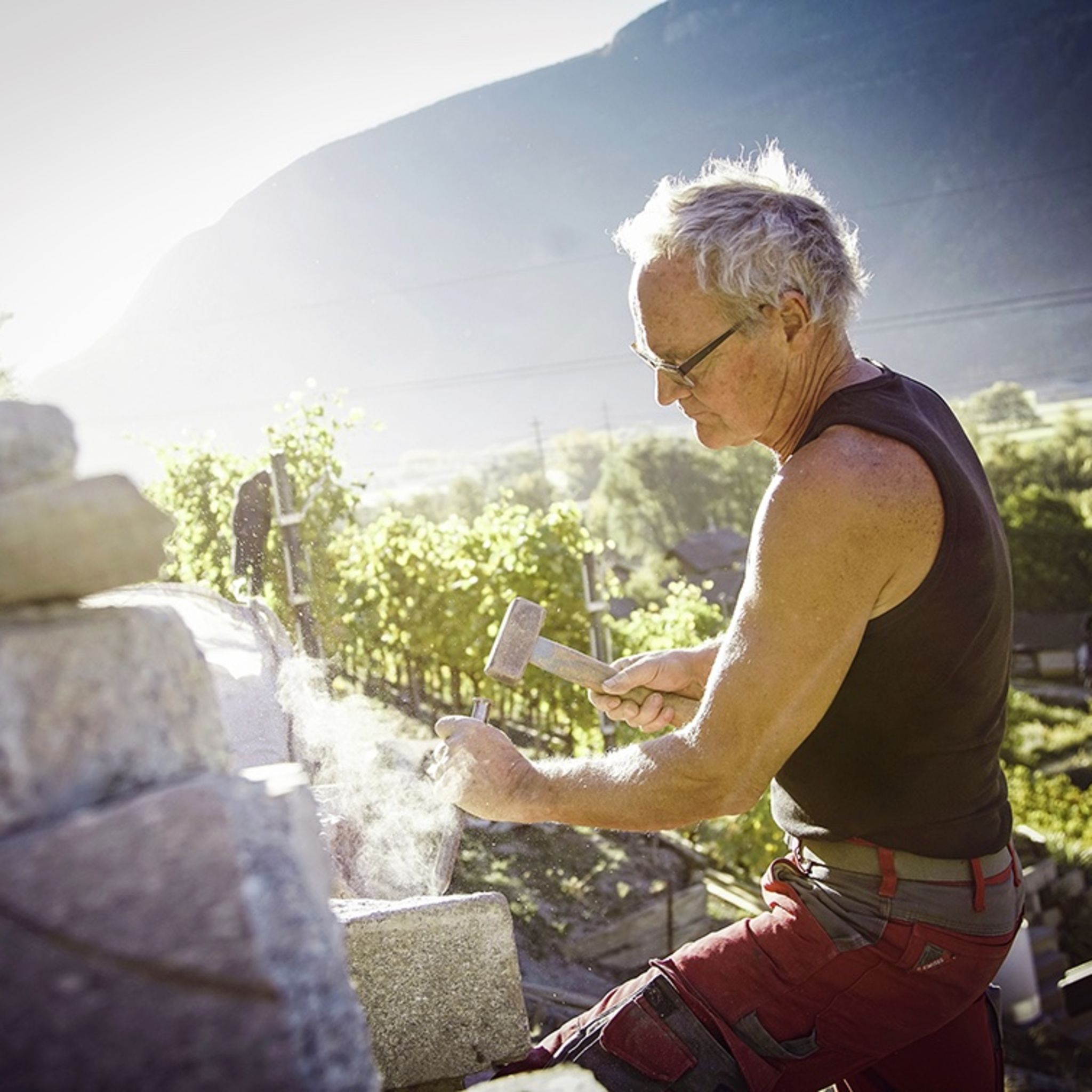 Beat Locher en plein travail. Avec son associé, il s'est spécialisé dans la réfection et l'entretien des murs en pierre sèche. Valais, Suisse.