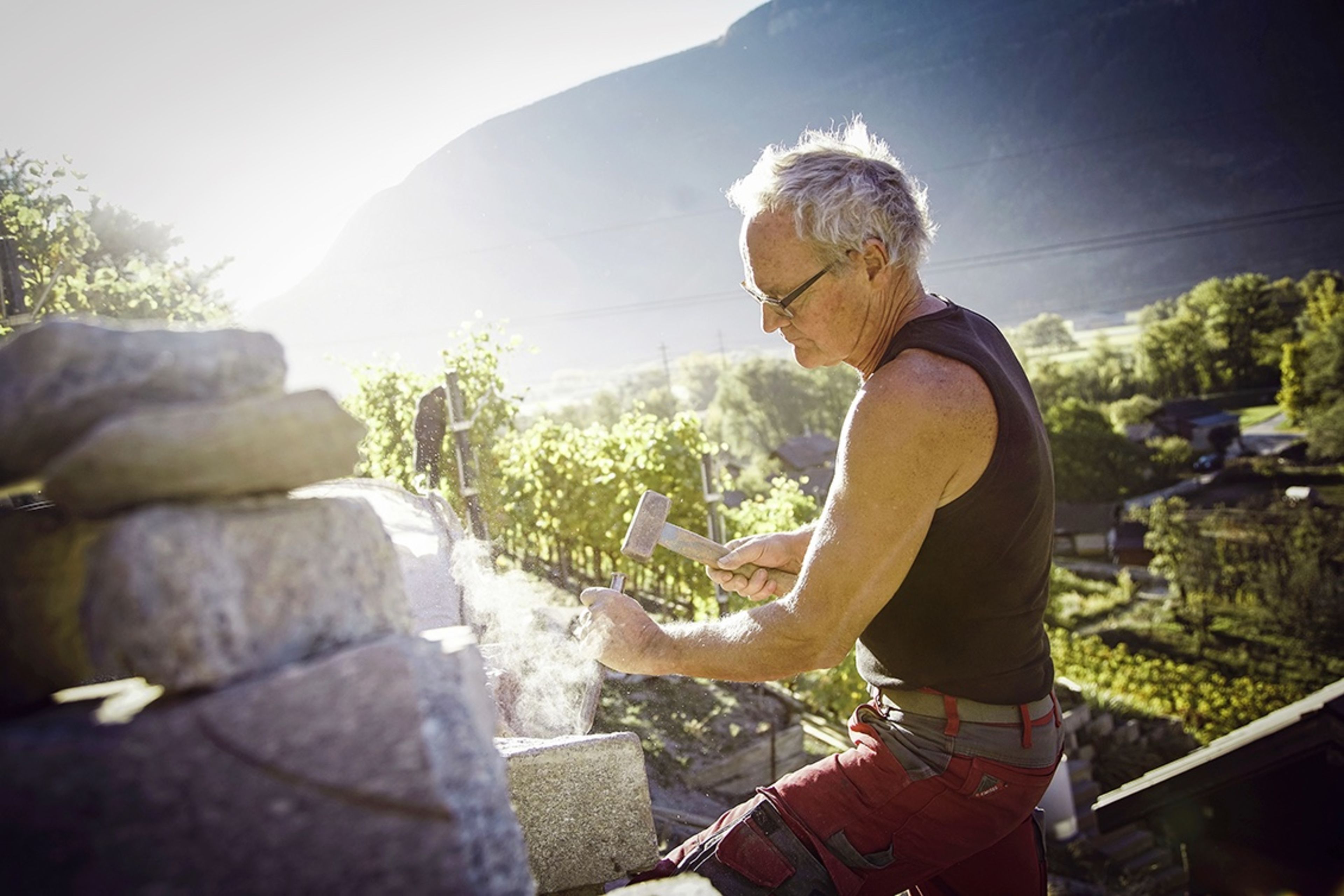 Beat Locher en plein travail. Avec son associé, il s'est spécialisé dans la réfection et l'entretien des murs en pierre sèche. Valais, Suisse.