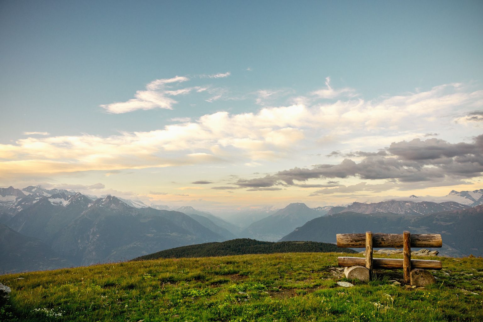 Wooden bench on the Moosalp with a wide Alpine panorama at sunset, Valais, Switzerland