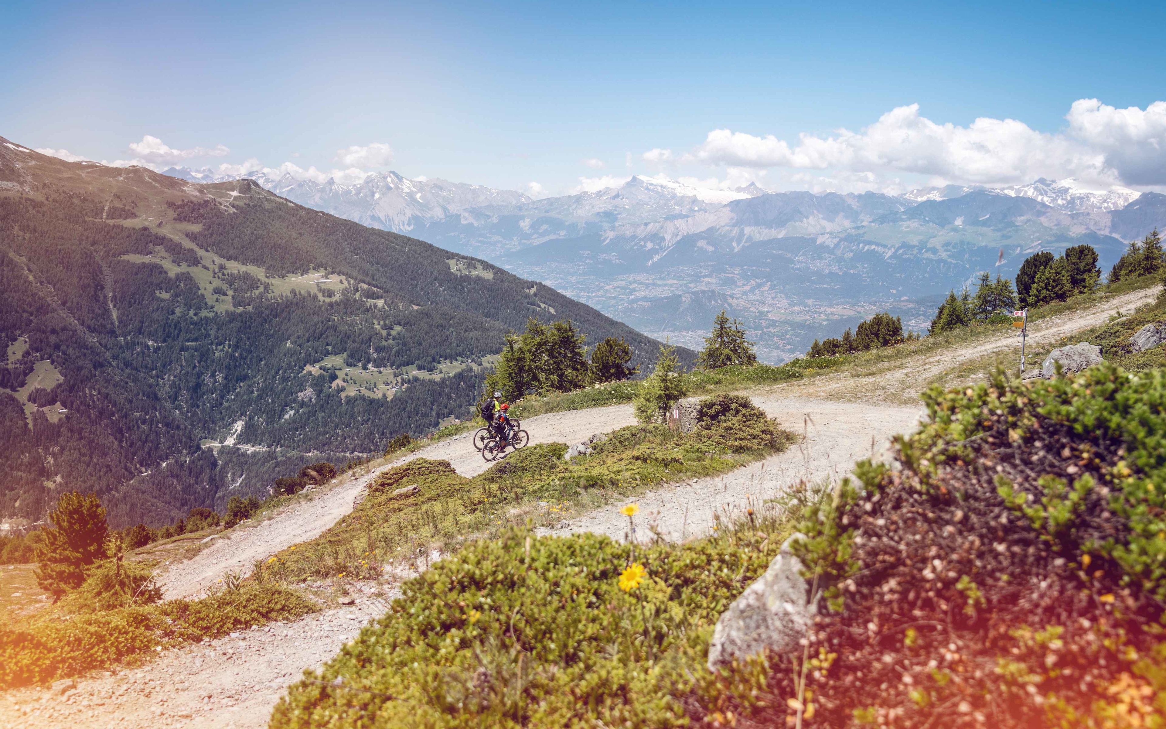 2 people on an e-bike on a climb with a magnificent view, Valais Switzerland