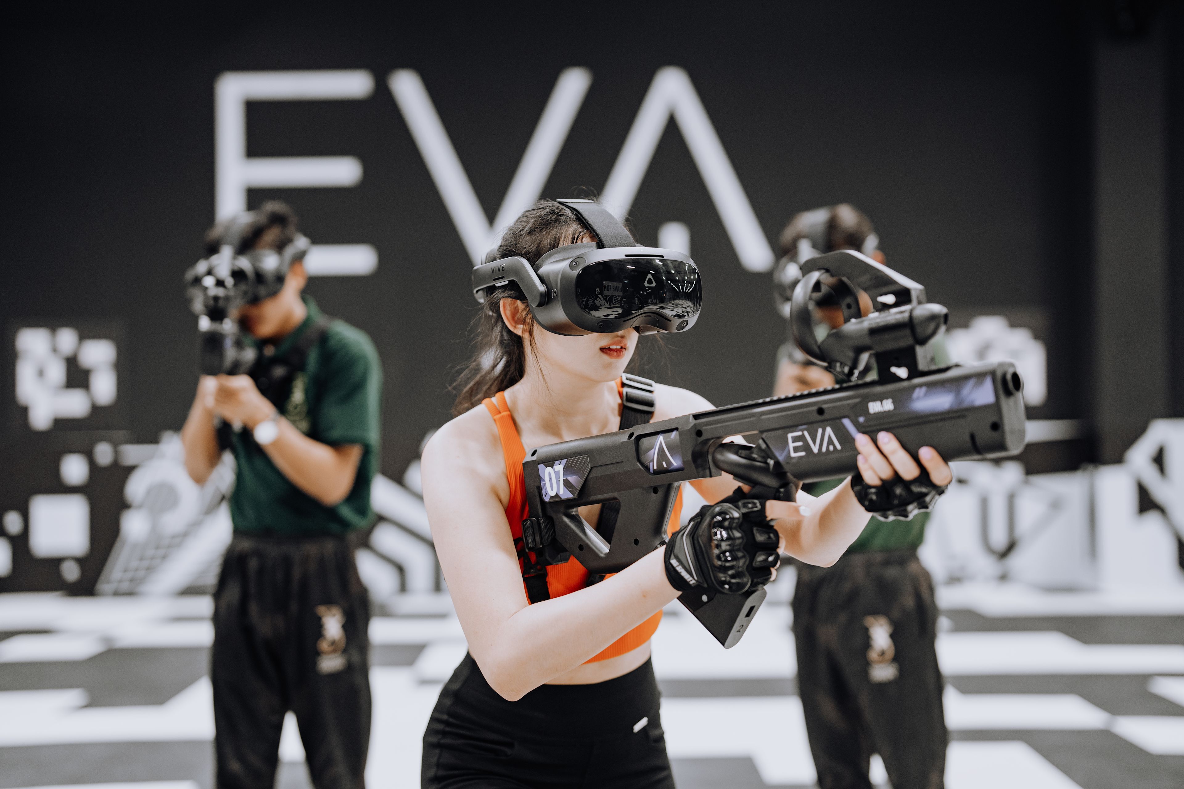 Drei Spieler mit VR-Headsets und futuristischen Waffen beim Spielen in einer EVA-eSports-Arena, Martigny, Wallis, Schweiz