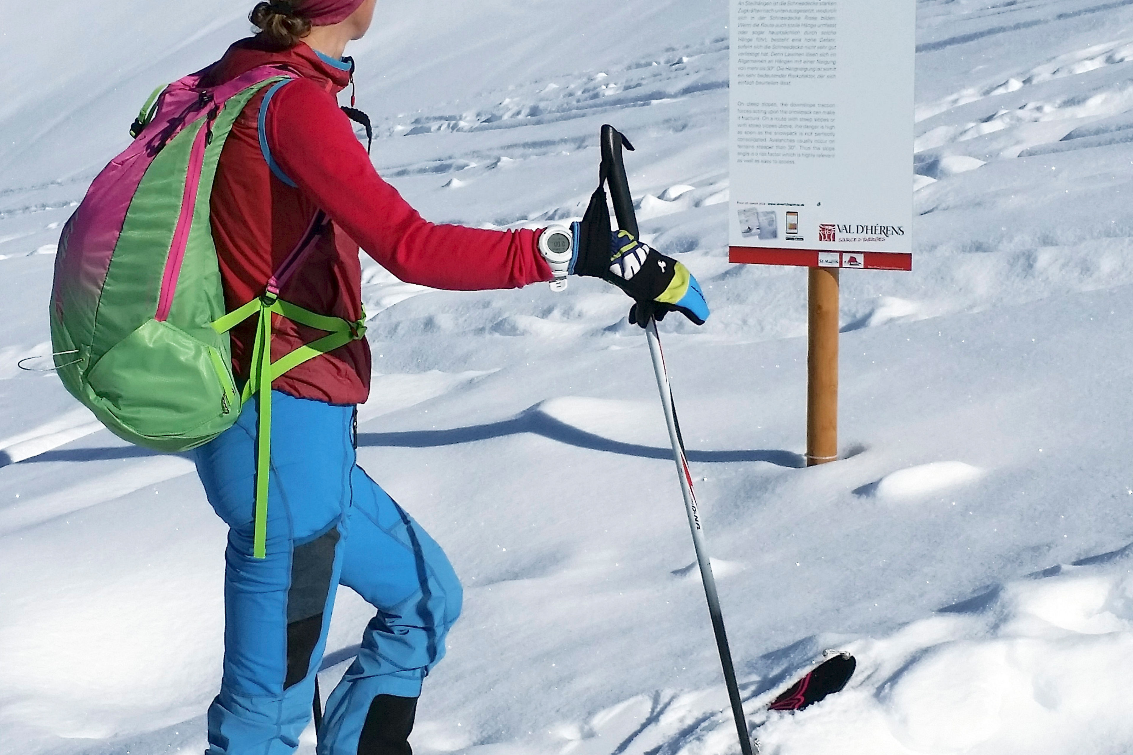 Skitourengeherin liest Infotafel des Nivo Trails im verschneiten Val d’Hérens