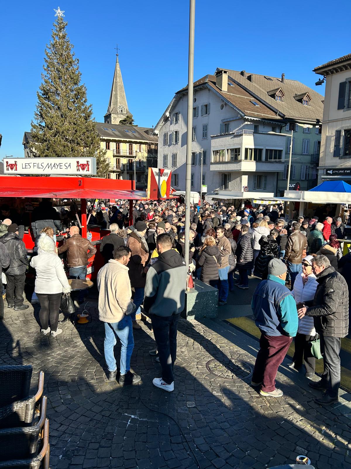 Foule rassemblée sur la place centrale de Monthey avec stands de restauration, musique et ambiance festive lors de la Foire du 31 décembre