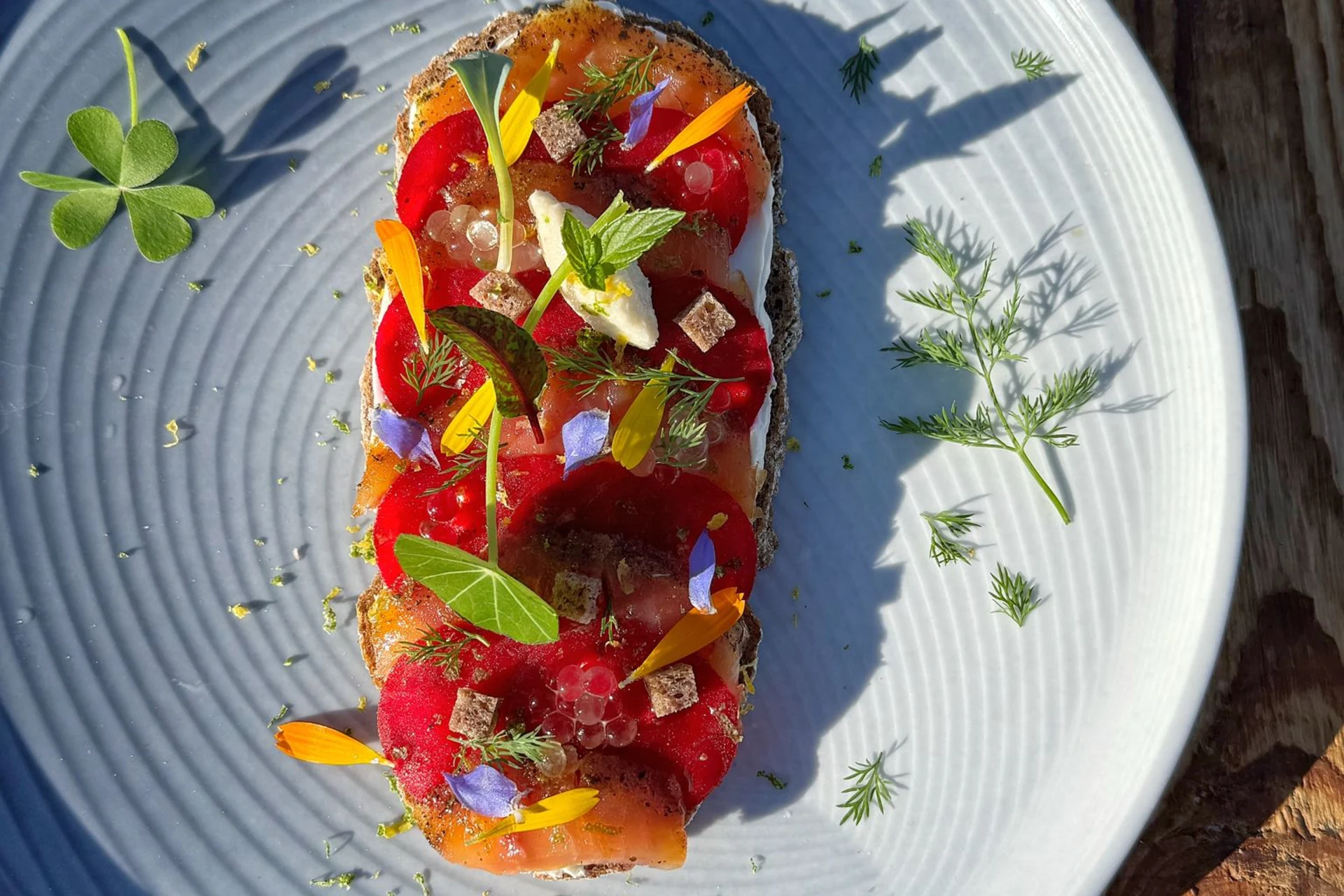 Fein angerichtete Tartine mit Walliser Produkten, essbaren Blumen und frischen Kräutern