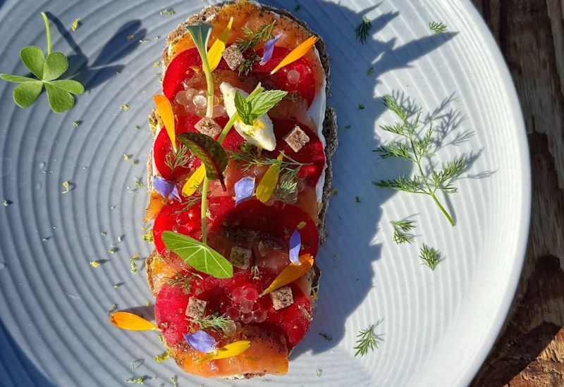 Fein angerichtete Tartine mit Walliser Produkten, essbaren Blumen und frischen Kräutern