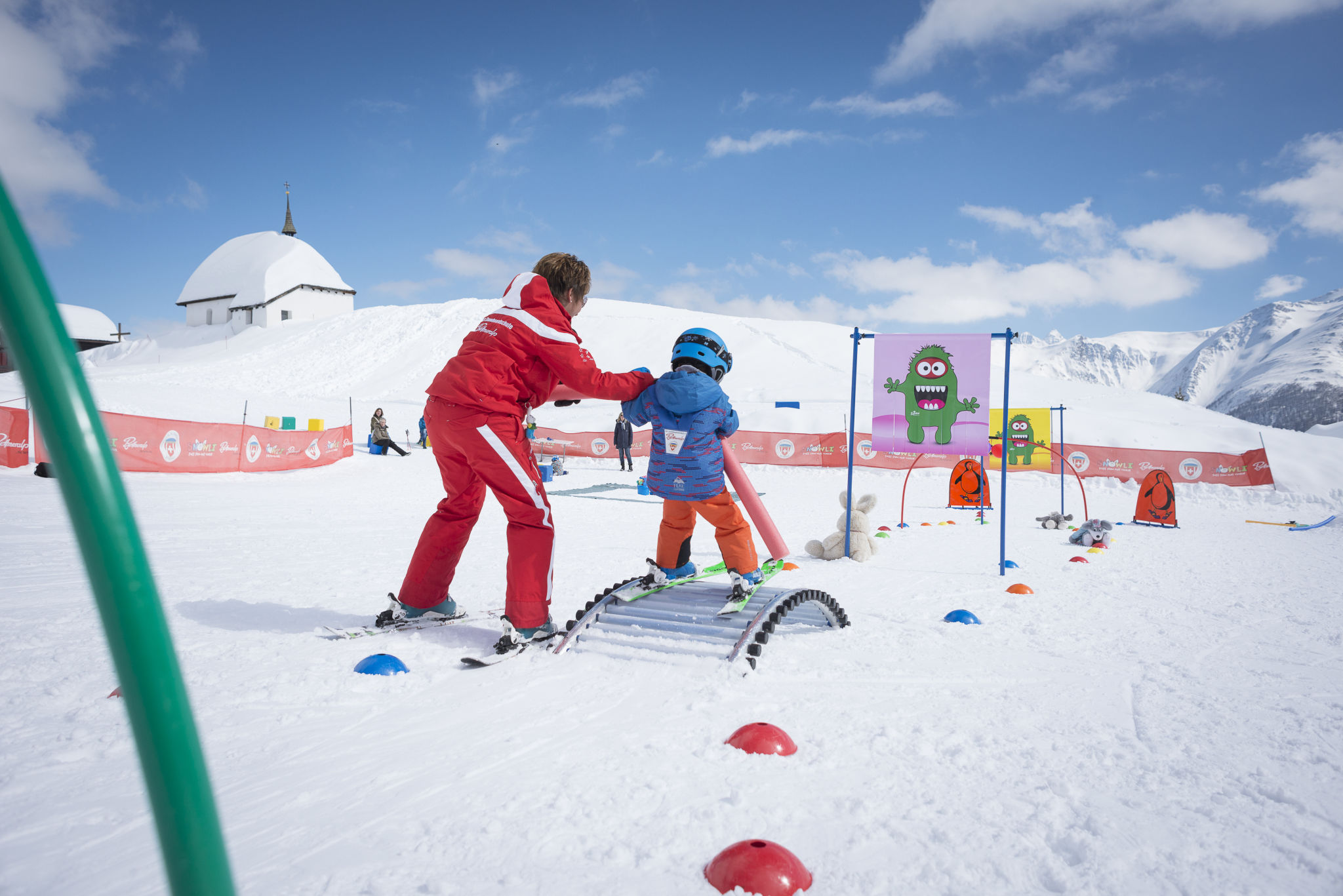A small child learns to ski in Bettmeralp's Children's snow playground with the help of his instructor