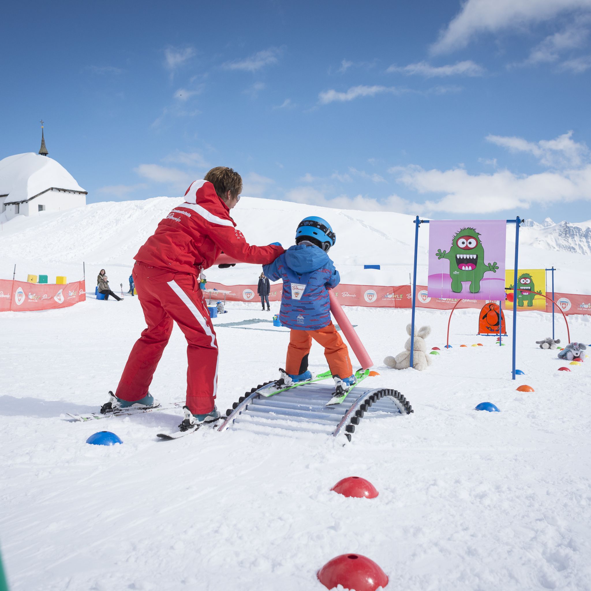Un petit enfant apprend le ski au jardin des neiges à Bettmeralp à l'aide de sa monitrice