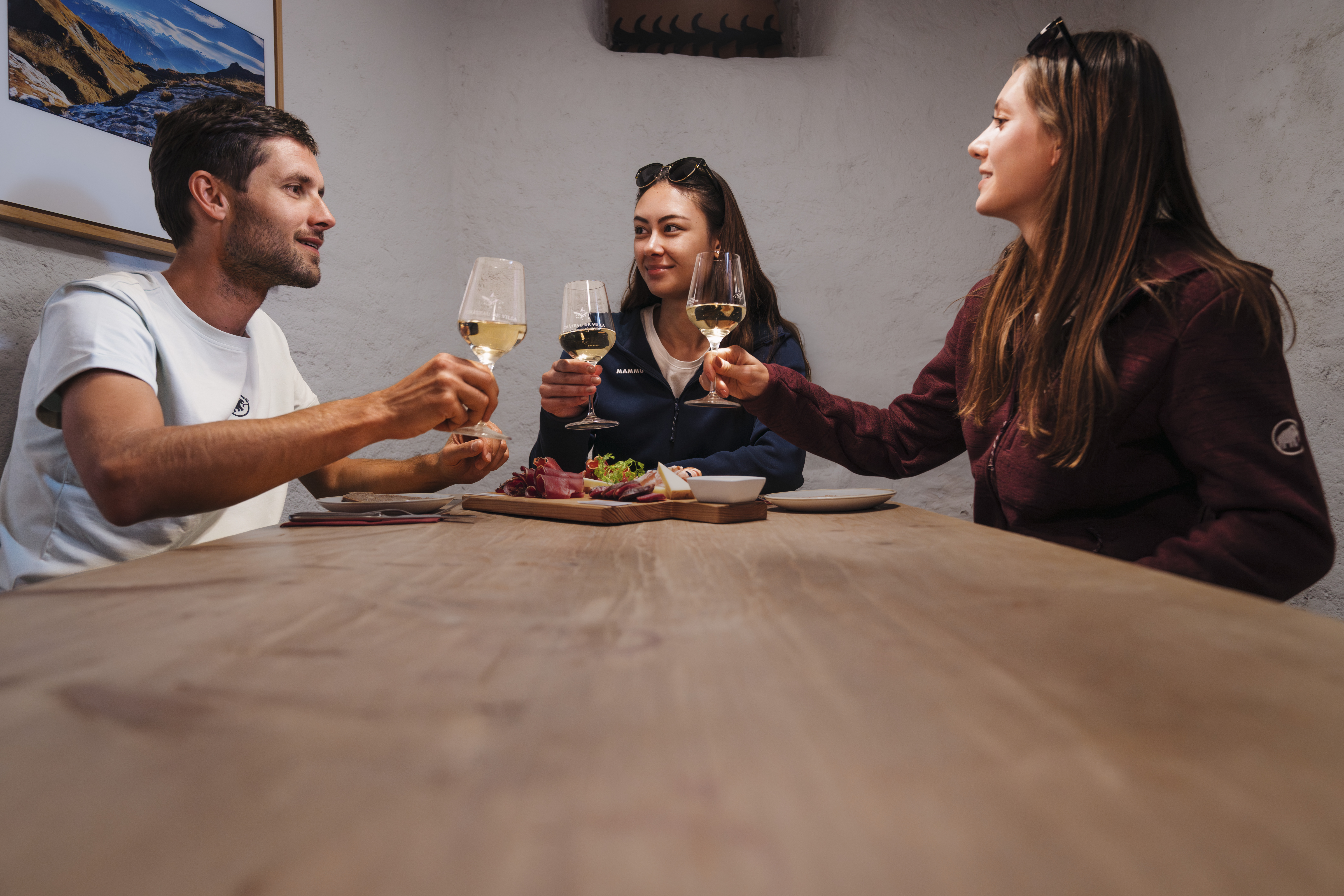 Trois personnes trinquent autour de spécialités valaisannes et de vin blanc au Château de Villa, Valais, Suisse