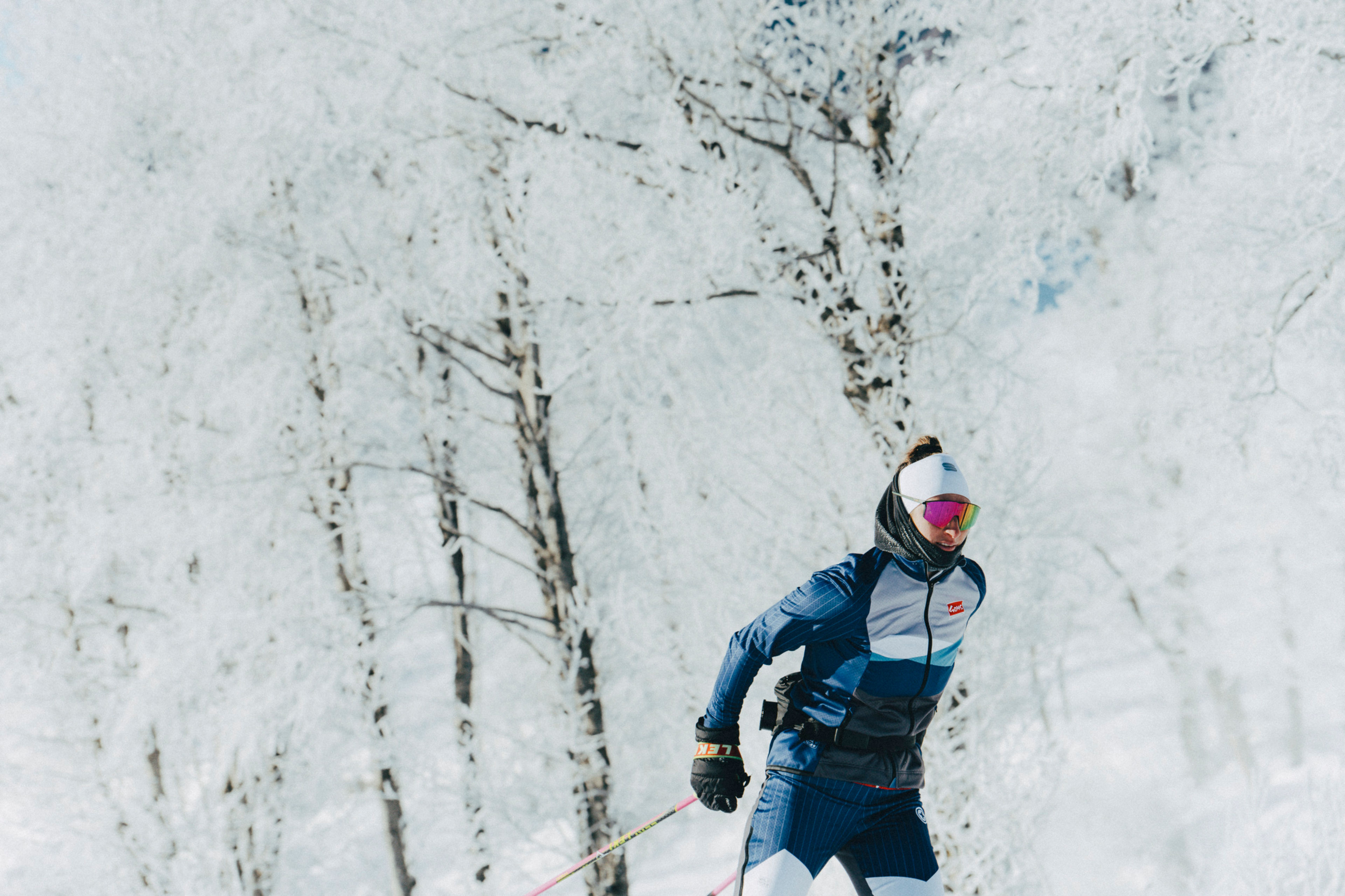 Nahaufnahme einer Langläuferin im verschneiten Wald von Goms, bei frostigem Winterwetter