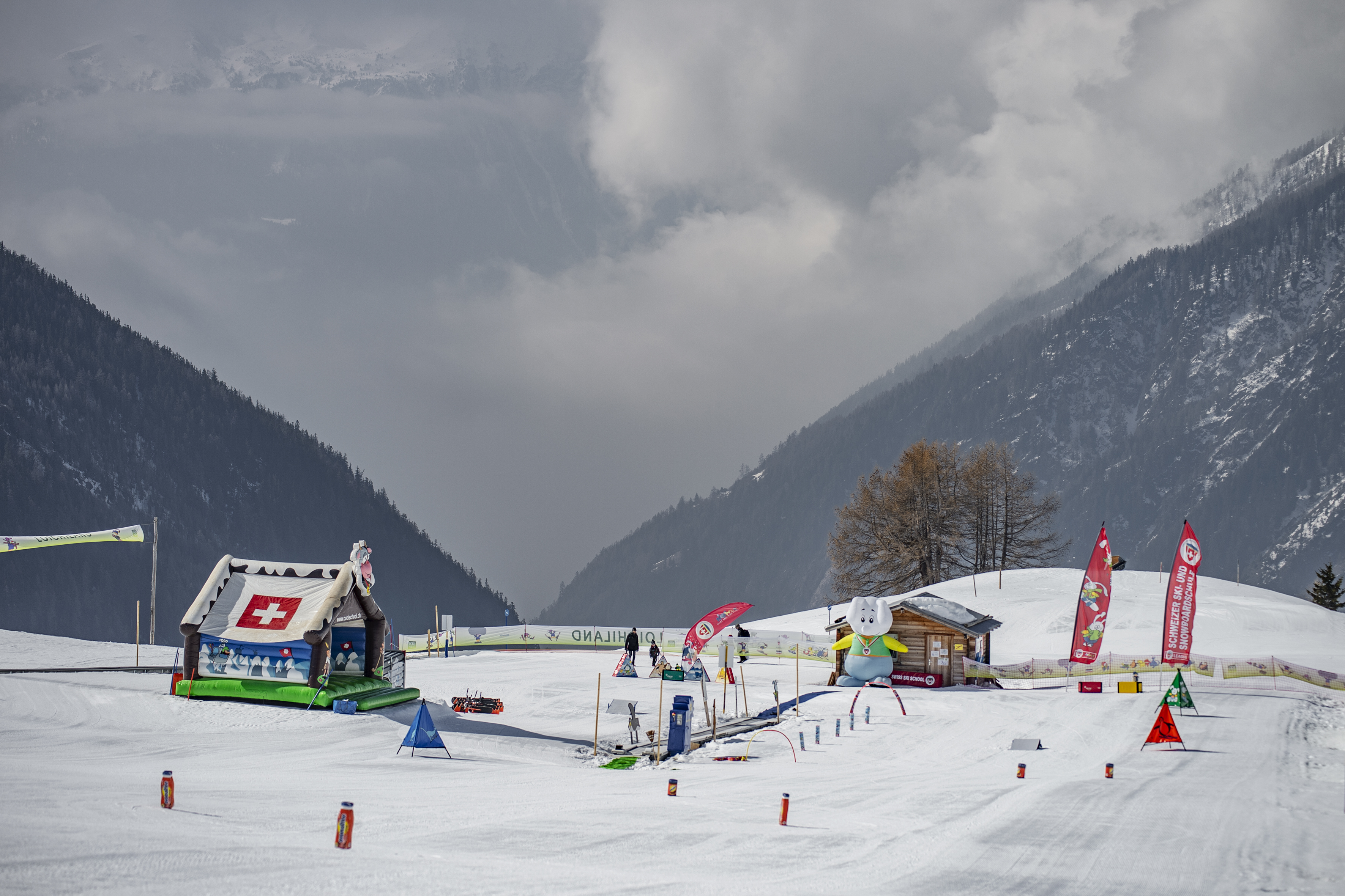 Espace enfants « Pays de Loichi » avec drapeaux, personnages ludiques et zone d’entraînement enneigée