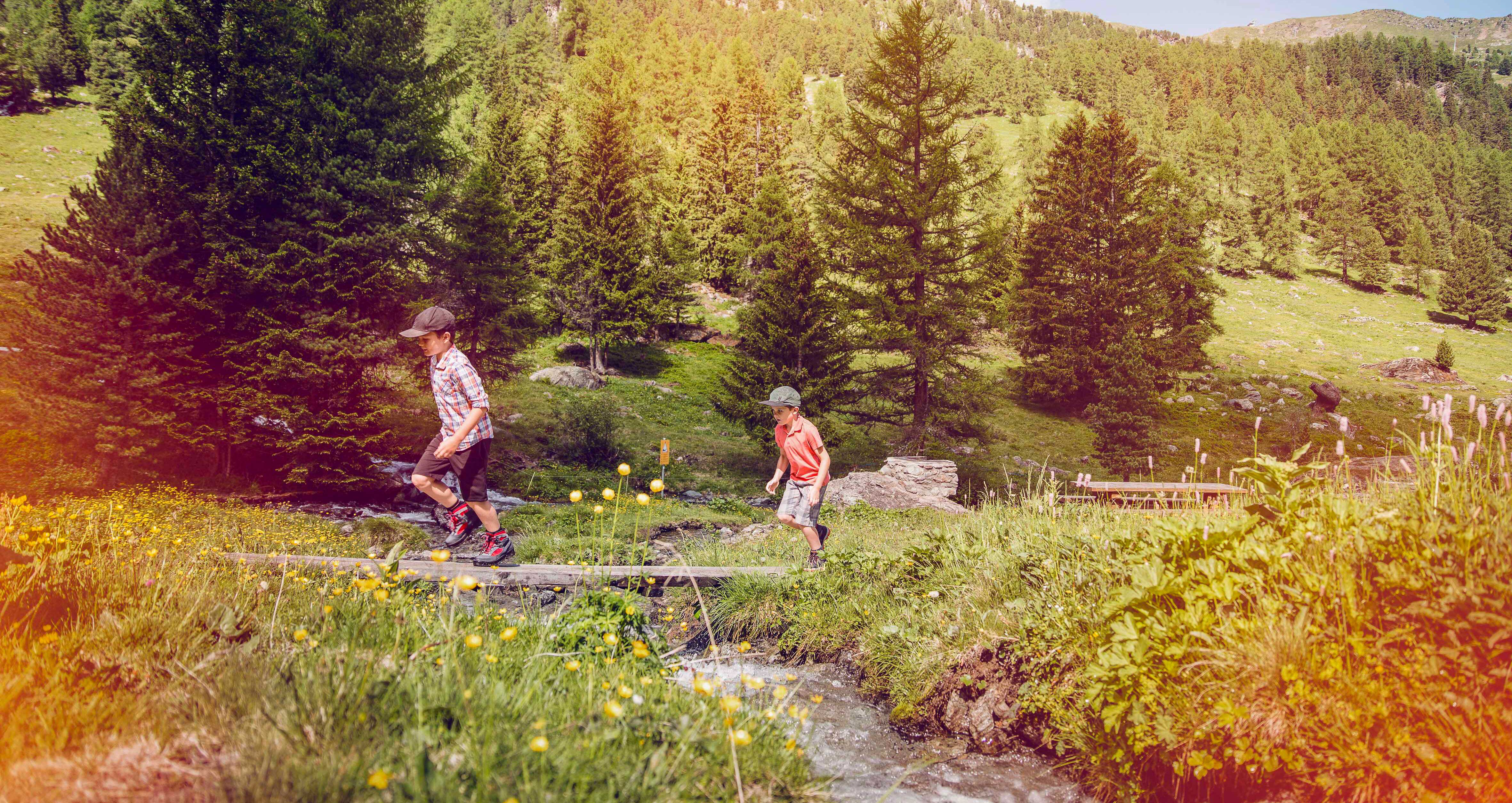 Kinder überqueren einen Steg in Nendaz. Spaziergang mit der Familie. Wallis, Schweiz