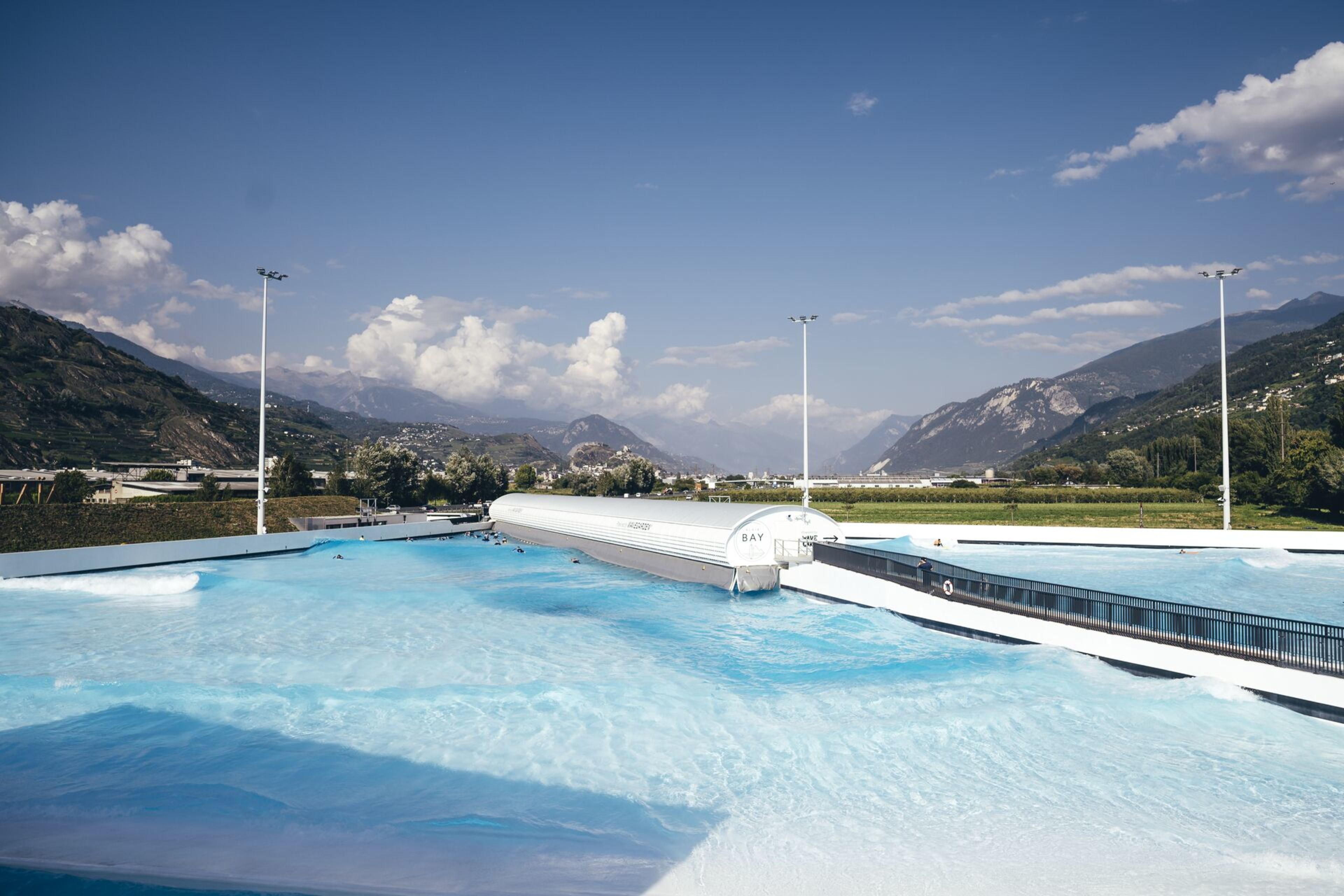 View of the Alaïa Bay surf park in Sion, Valais – an artificial wave pool with the Valais Alps in the background.