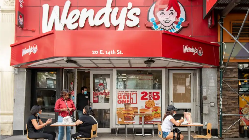 A Wendy's outlet with outdoor seating for customers.