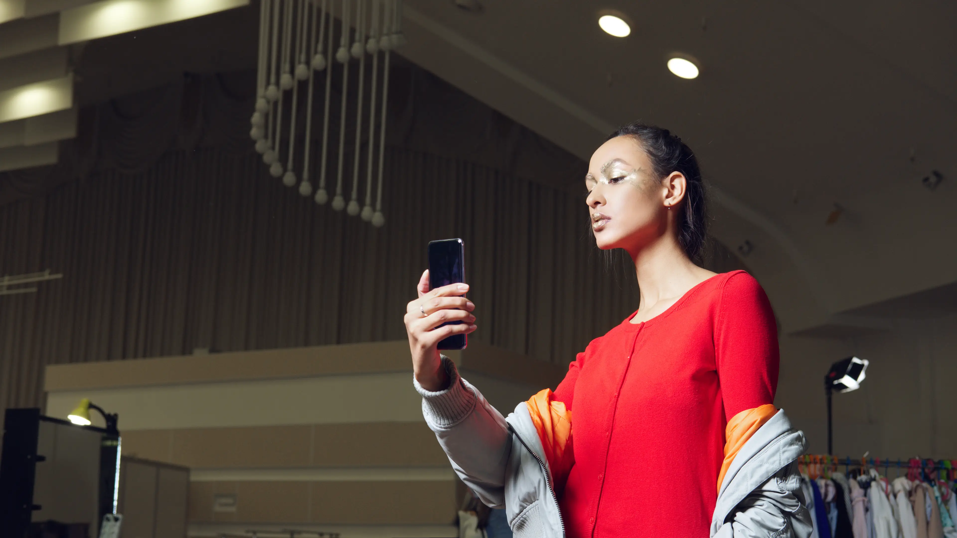 Pretty girl making selfie during preparation to the show. Model getting ready at backstage with makeup and hair.