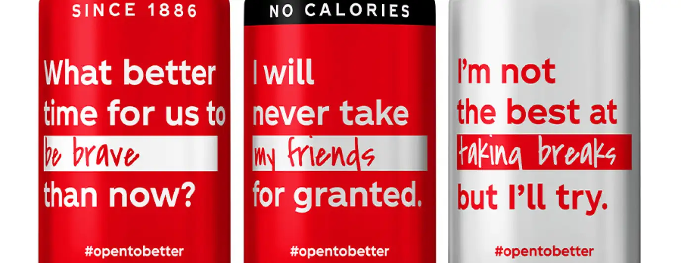 Three Coca-Cola cans featuring the campaign #openbetter