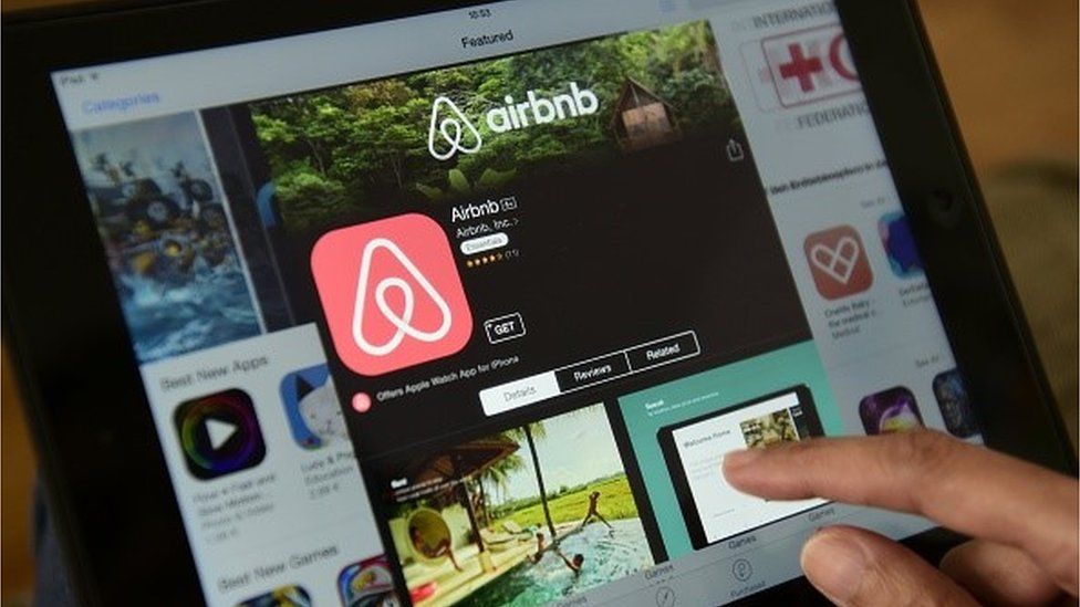 A person getting more details about the Airbnb app on an app store on their tablet.