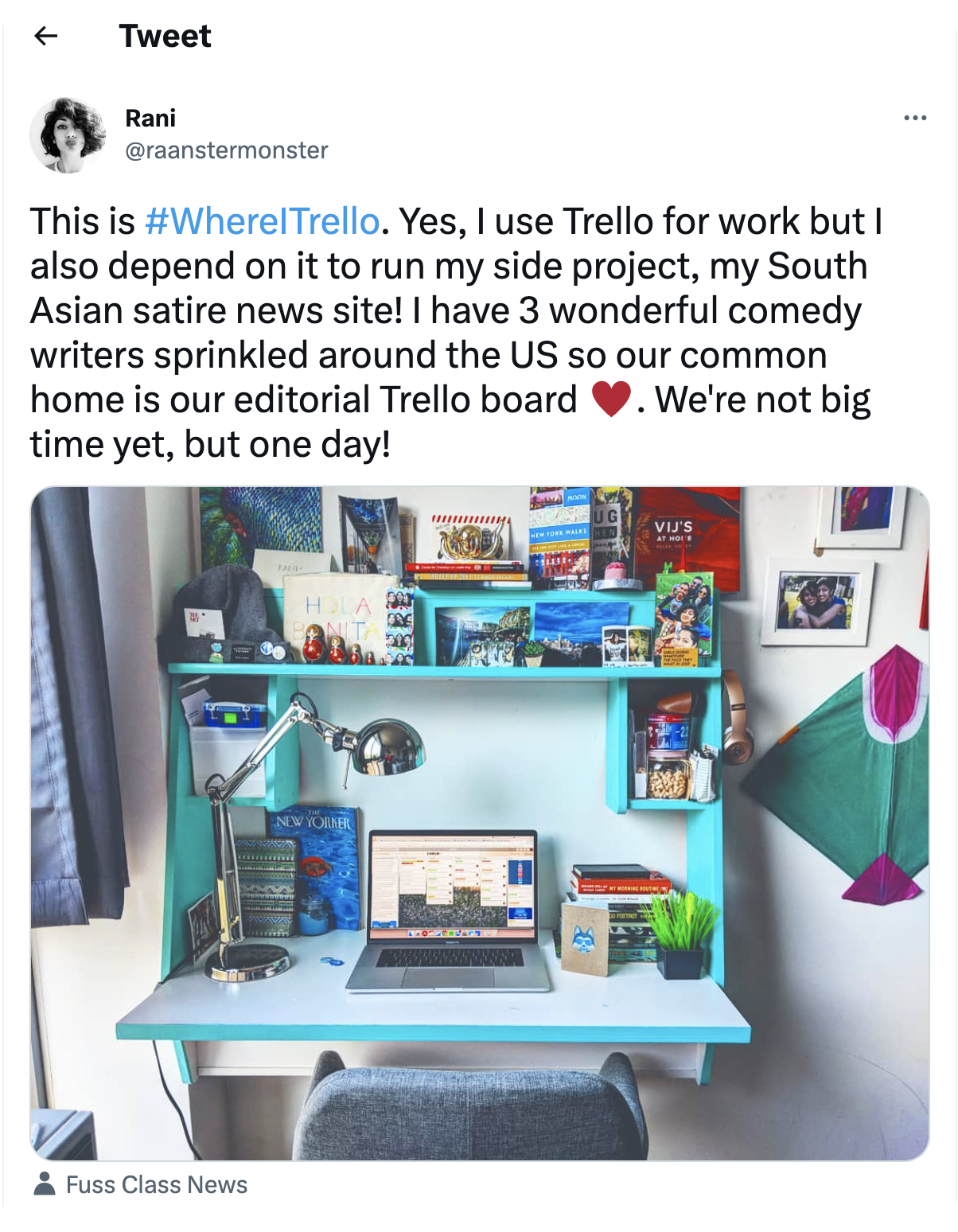 A Tweet from a Trello user with a pic of a laptop on a workstation. The laptop shows a news site, and the Tweet caption says that Tweeter uses Trello for work and their satire news site, and they hope to make it big one day.